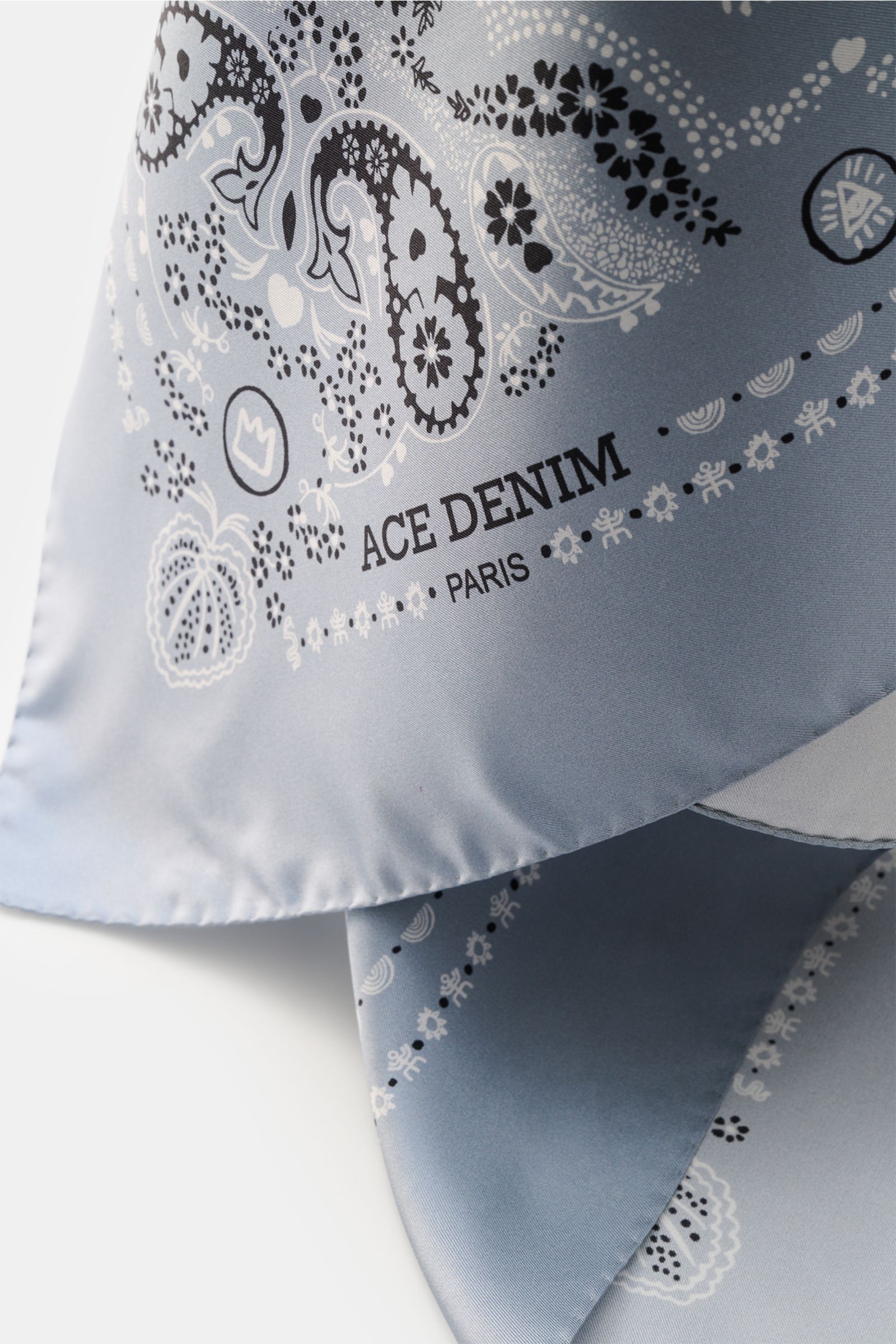 Close-up front perspective of the Ace Denim Silk scarf smoky blue/black/white patterned with paisley design, pure silk, soft feel, 90x90 cm. Eye-catching for the warm season: The ACE DENIM silk scarf in a bandana design is a casual statement accessory for