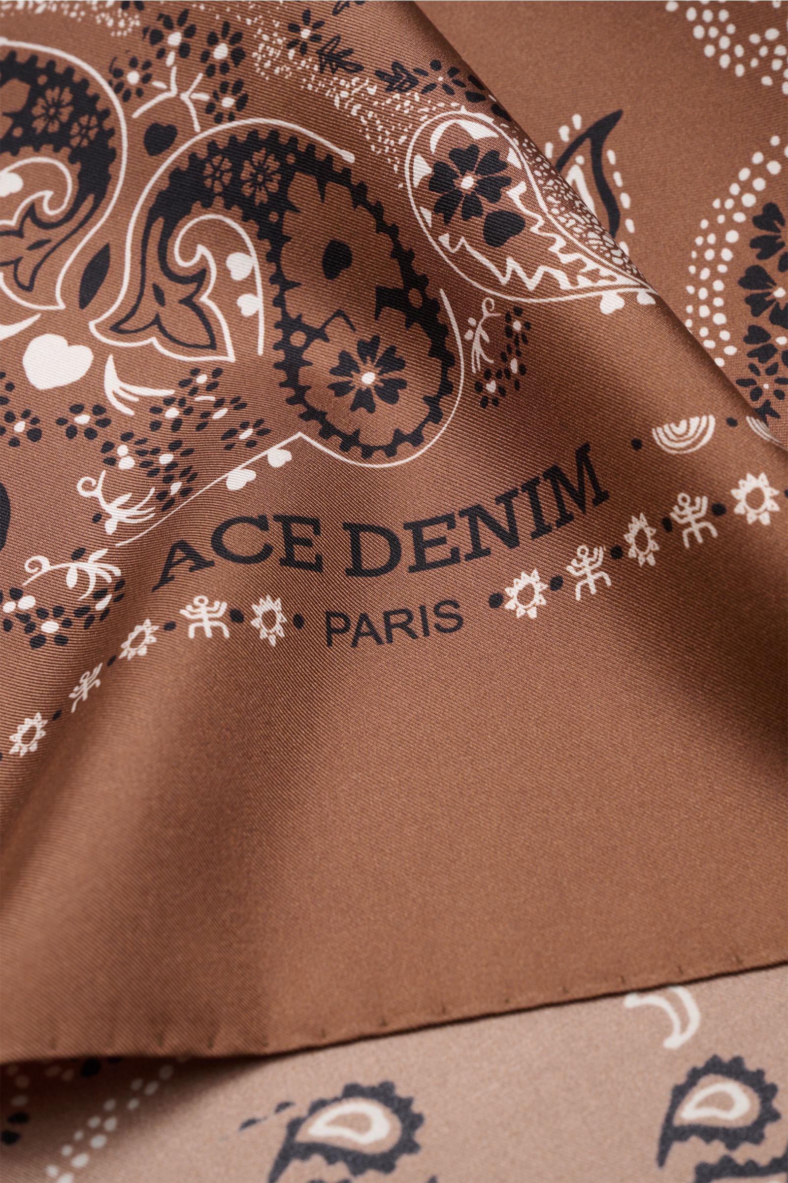 Close-up shot of the Ace Denim Silk scarf brown/black/white patterned, showcasing its paisley design and smooth texture. 

Eye-catching for the warm season: The ACE DENIM silk scarf in a bandana design is a casual statement accessory for summer looks.