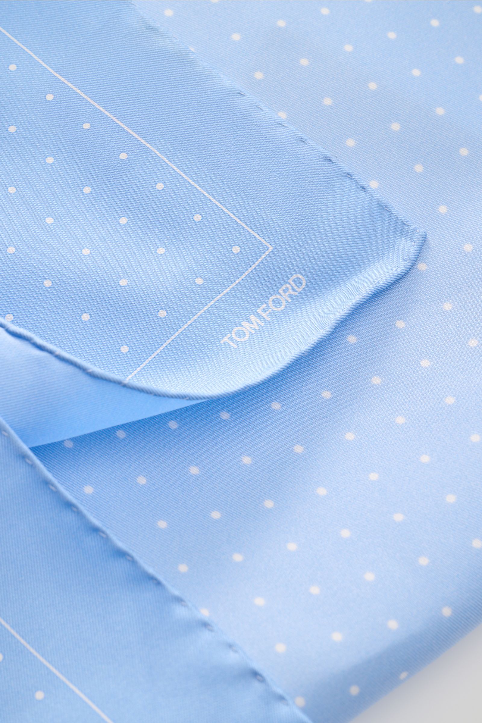Close-up top view of Tom Ford Seiden-Einstecktuch hellblau/weiß gepunktet with pure silk, smooth feel, rolled edges, small TOM FORD print.

Description: Dieses Einstecktuch von TOM FORD aus reiner Seide setzt mit seinem dezenten Punktmuster und den rol