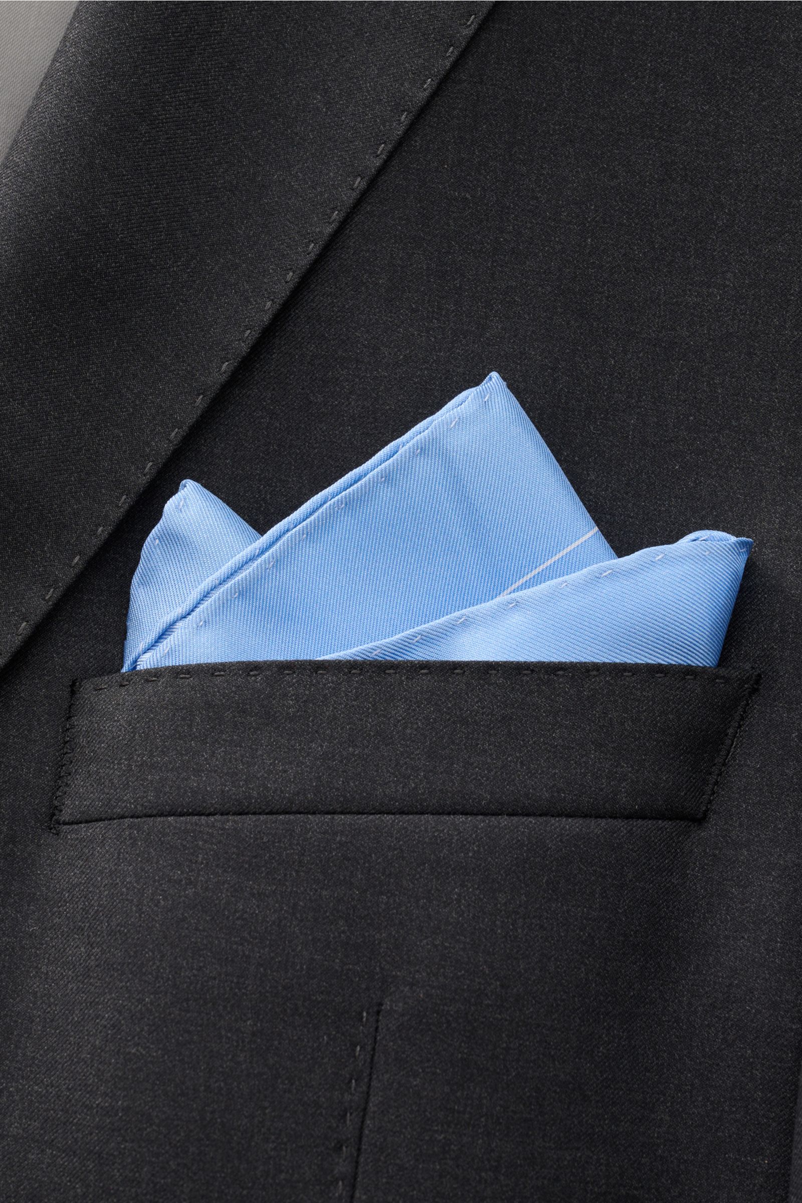 Front close-up of a black jacket pocket with a light blue and white dotted Tom Ford Seiden-Einstecktuch hellblau/weiß gepunktet silk pocket square with rolled edges.

Description: Dieses Einstecktuch von TOM FORD aus reiner Seide setzt mit seinem dezen