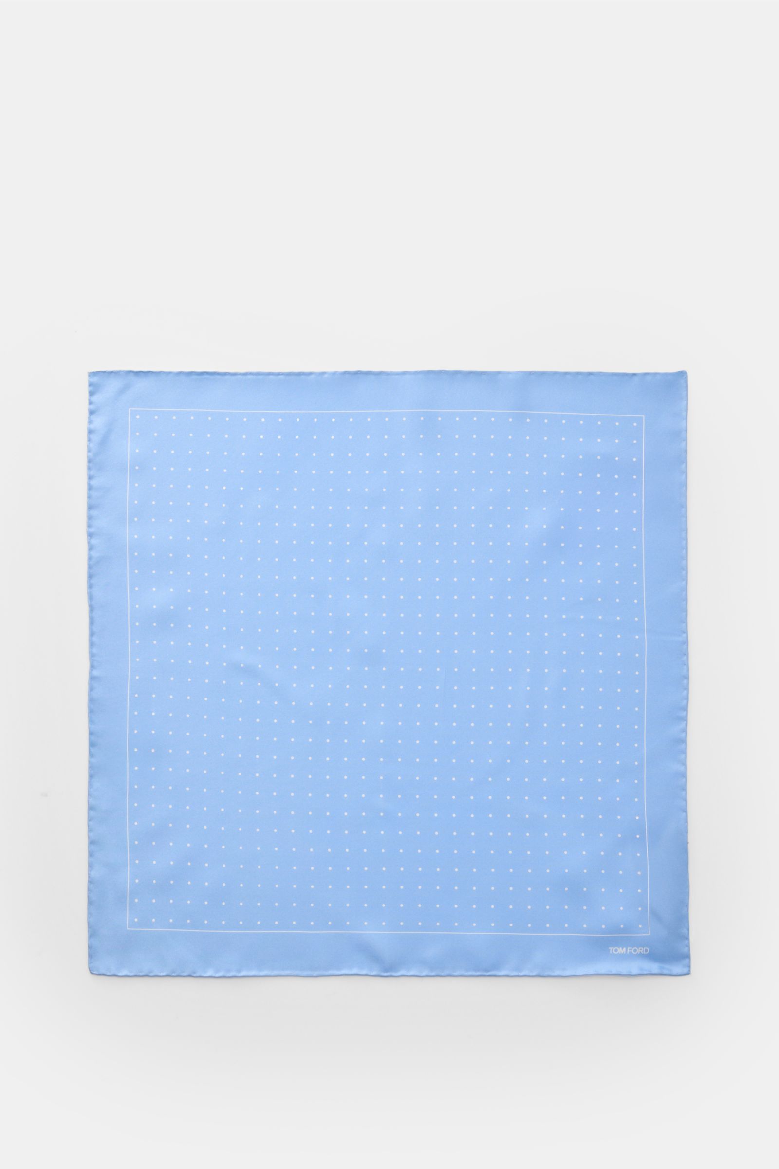 Top-down view of Tom Ford Seiden-Einstecktuch hellblau/weiß gepunktet, a light blue silk pocket square with white polka dots, rolled edges, and a subtle TOM FORD print.

Dieses Einstecktuch von TOM FORD aus reiner Seide setzt mit seinem dezenten Punktm