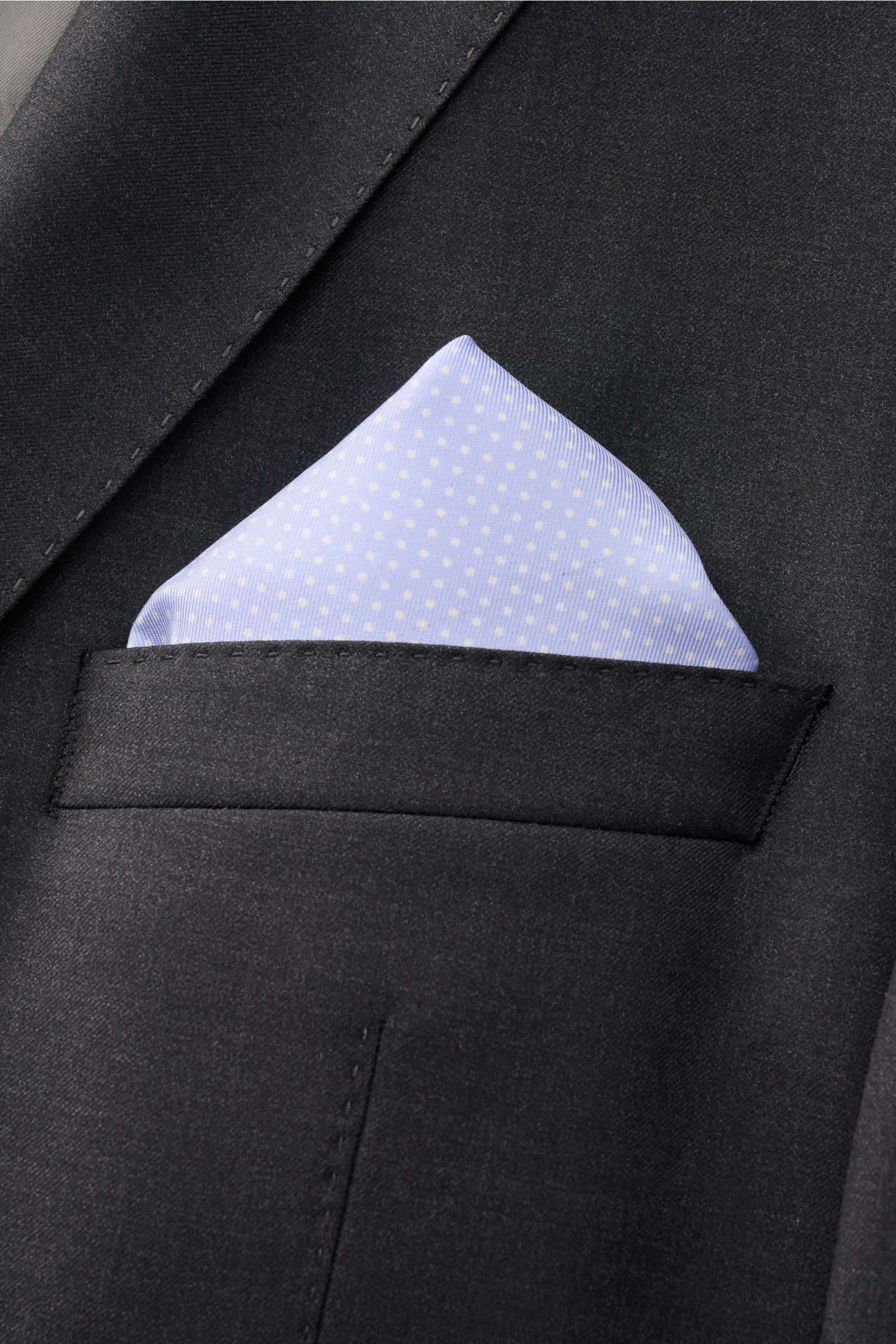 Close-up front view of a black suit jacket pocket with a light blue and white polka-dotted Tom Ford Seiden-Einstecktuch hellblau/weiß gepunktet made of pure silk.

Description: Dieses Einstecktuch von TOM FORD aus reiner Seide setzt mit seinem dezenten