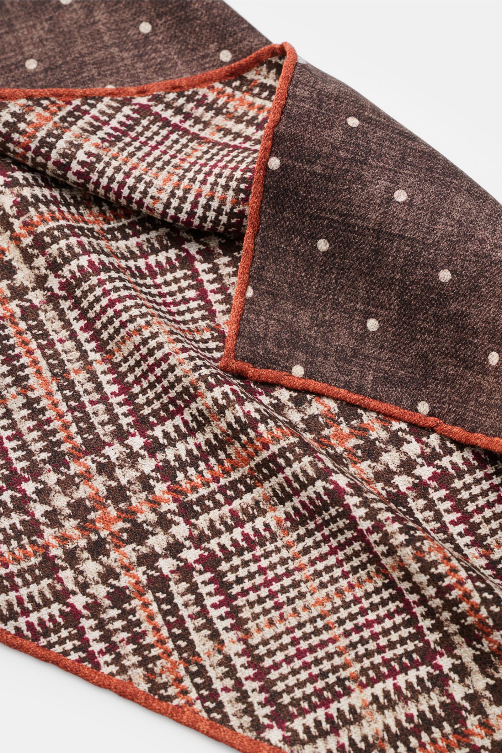 Close-up top-down view of the Brunello Cucinelli Seiden-Einstecktuch braun/orange/weiß gemustert showing Glencheck pattern with brown/orange/white dots on the reverse, hand-rolled edges. Features: 
- reine Seide
- geschmeidiger Griff
- Glencheck
- Punkte 