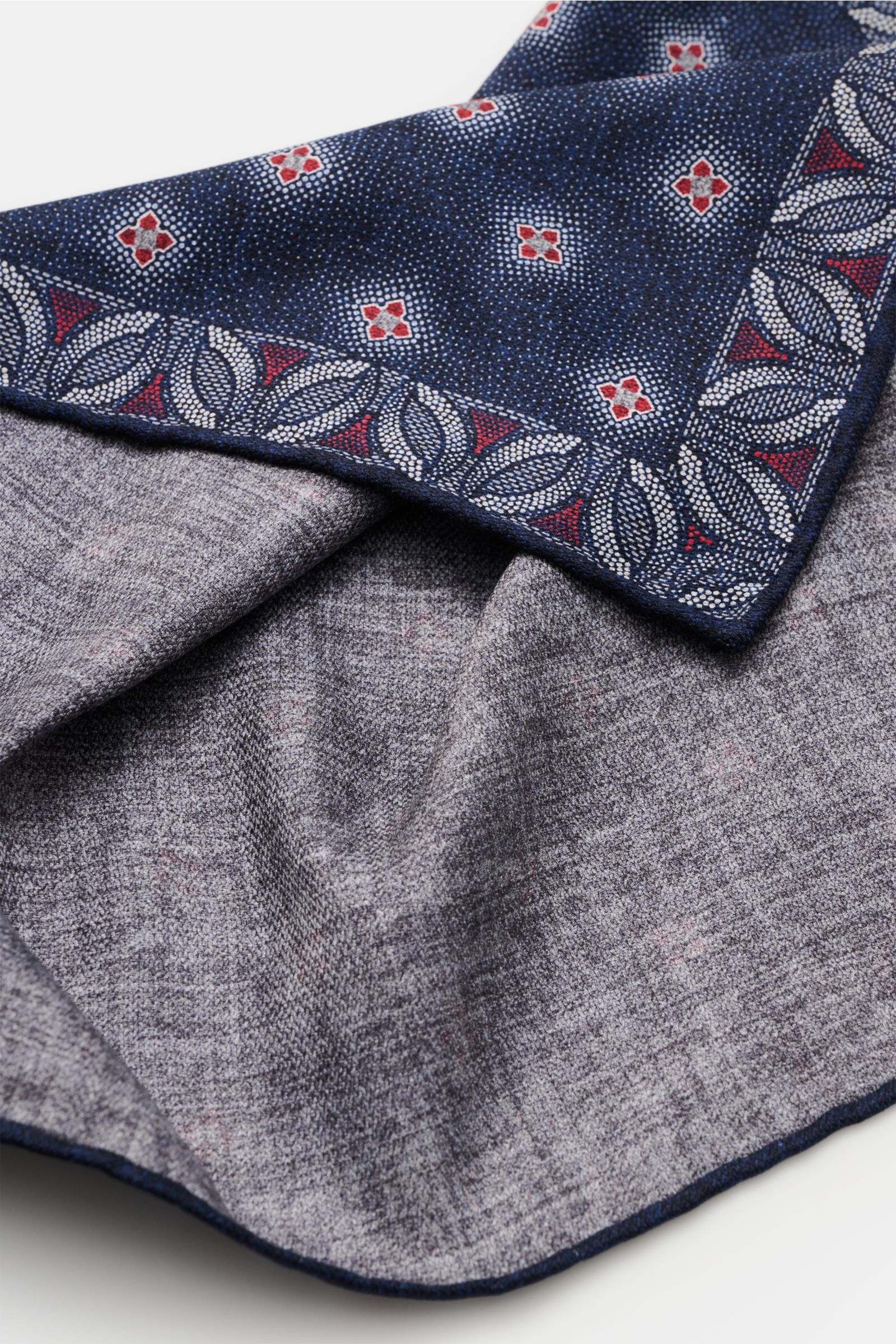 Close-up, angled view of the Brunello Cucinelli Seiden-Einstecktuch navy/grau/rot gemustert showing floral patterned navy silk with red and gray details, handrolled edges, and a smooth grey fabric reverse. Features: reine Seide, geschmeidiger Griff, flora