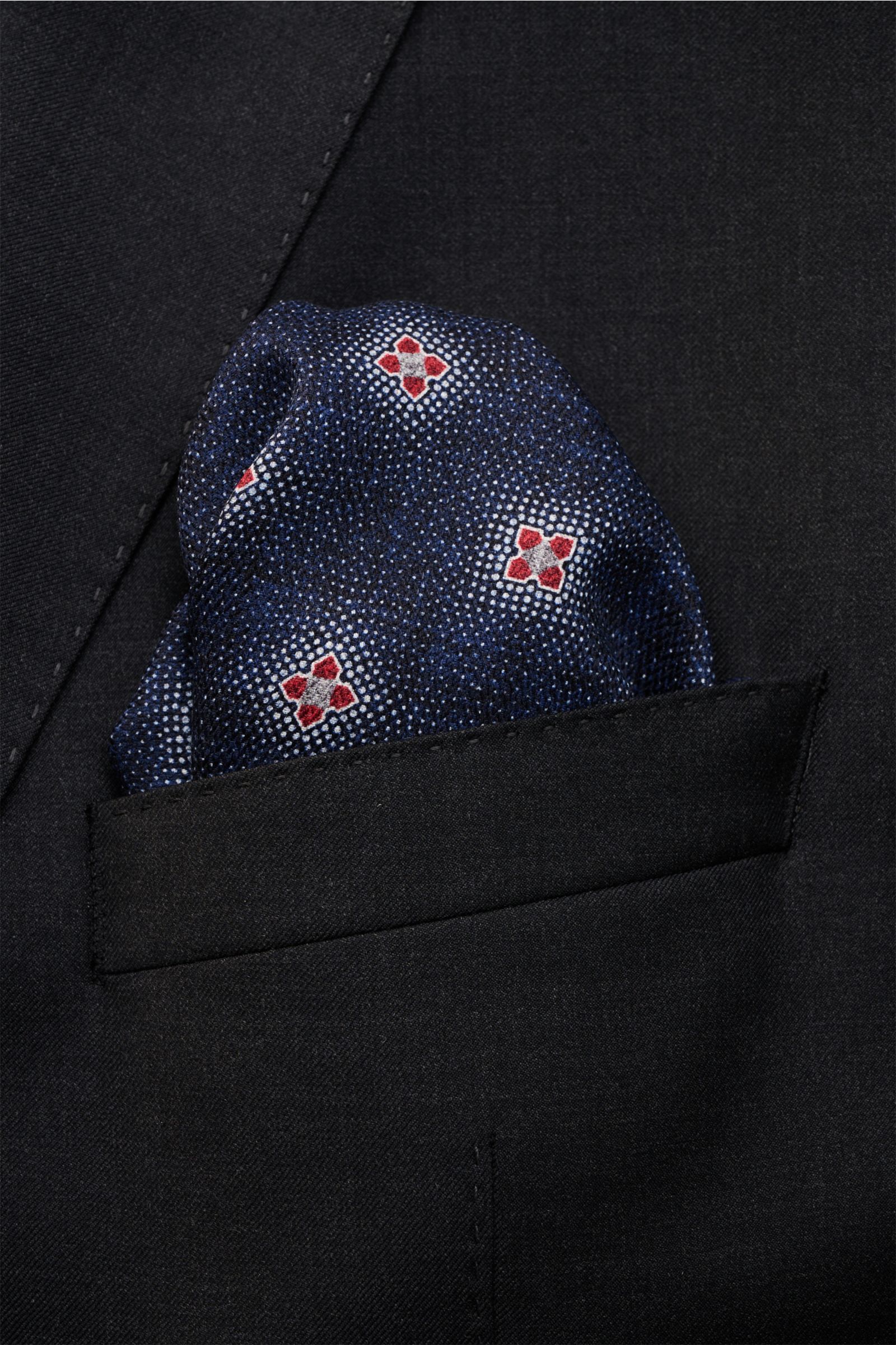 Close-up front view of a Brunello Cucinelli Seiden-Einstecktuch navy/grau/rot gemustert pocket square tucked into a black suit jacket pocket, featuring reine Seide, geschmeidiger Griff, floral gemustert, handrollierte Kanten, Made in Italy, Maße: ca. 35 c