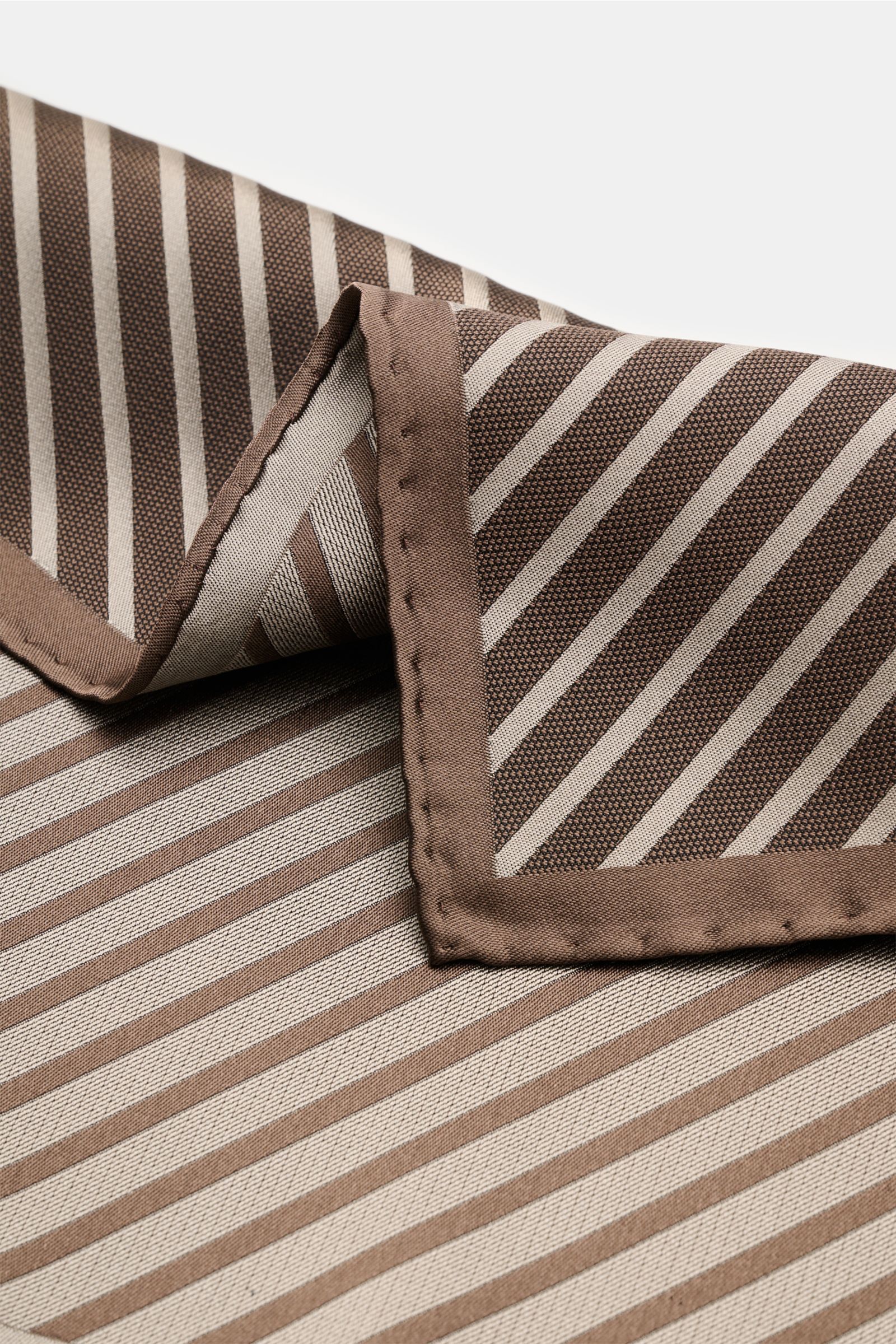 Close-up top view of the Brunello Cucinelli Seiden-Einstecktuch dunkelbraun/taupe gestreift showing striped pattern, hand-rolled edges, made of pure silk with smooth feel, made in Italy, approx. 35 cm x 35 cm.  

reine Seide
geschmeidiger