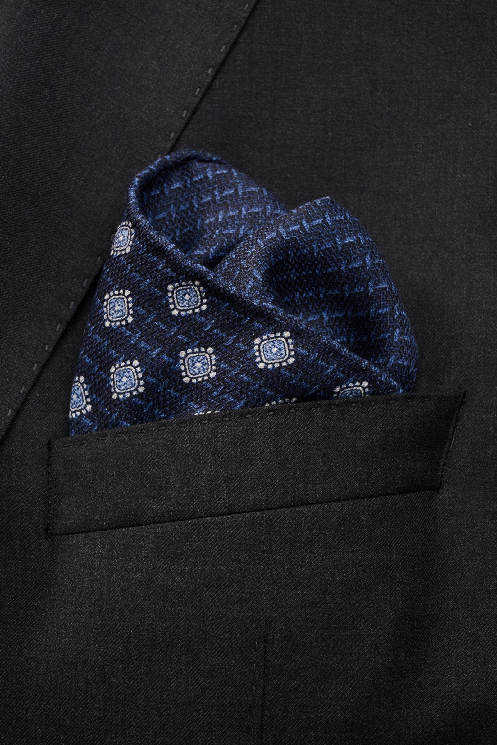 Front view of a Brunello Cucinelli Seiden-Einstecktuch dunkelrot/navy gemustert pocket square tucked into a dark suit jacket pocket, featuring reine Seide, geschmeidiger Griff, Ornament-Muster, handrollierte Kanten, Made in Italy, Maße: ca. 35 cm x 35 cm.
