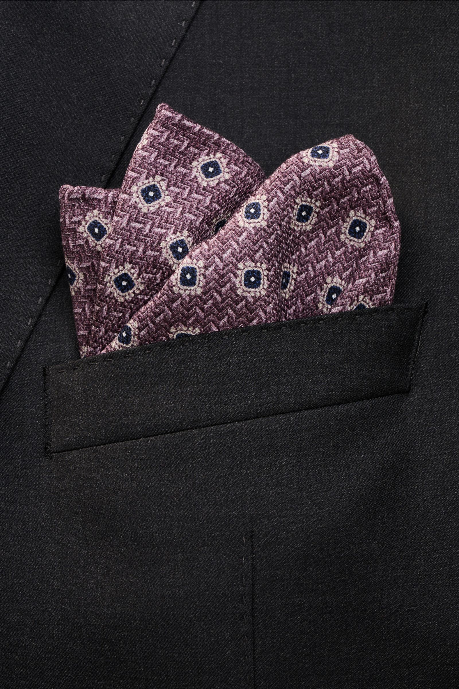 Brunello Cucinelli Seiden-Einstecktuch navy/rauchblau gepunktet shown from a close-up front angle in a black jacket pocket. Features reine Seide, geschmeidiger Griff, Punktemuster, handrollierte Kanten, Made in Italy, Maße: ca. 35 cm x 35 cm.
