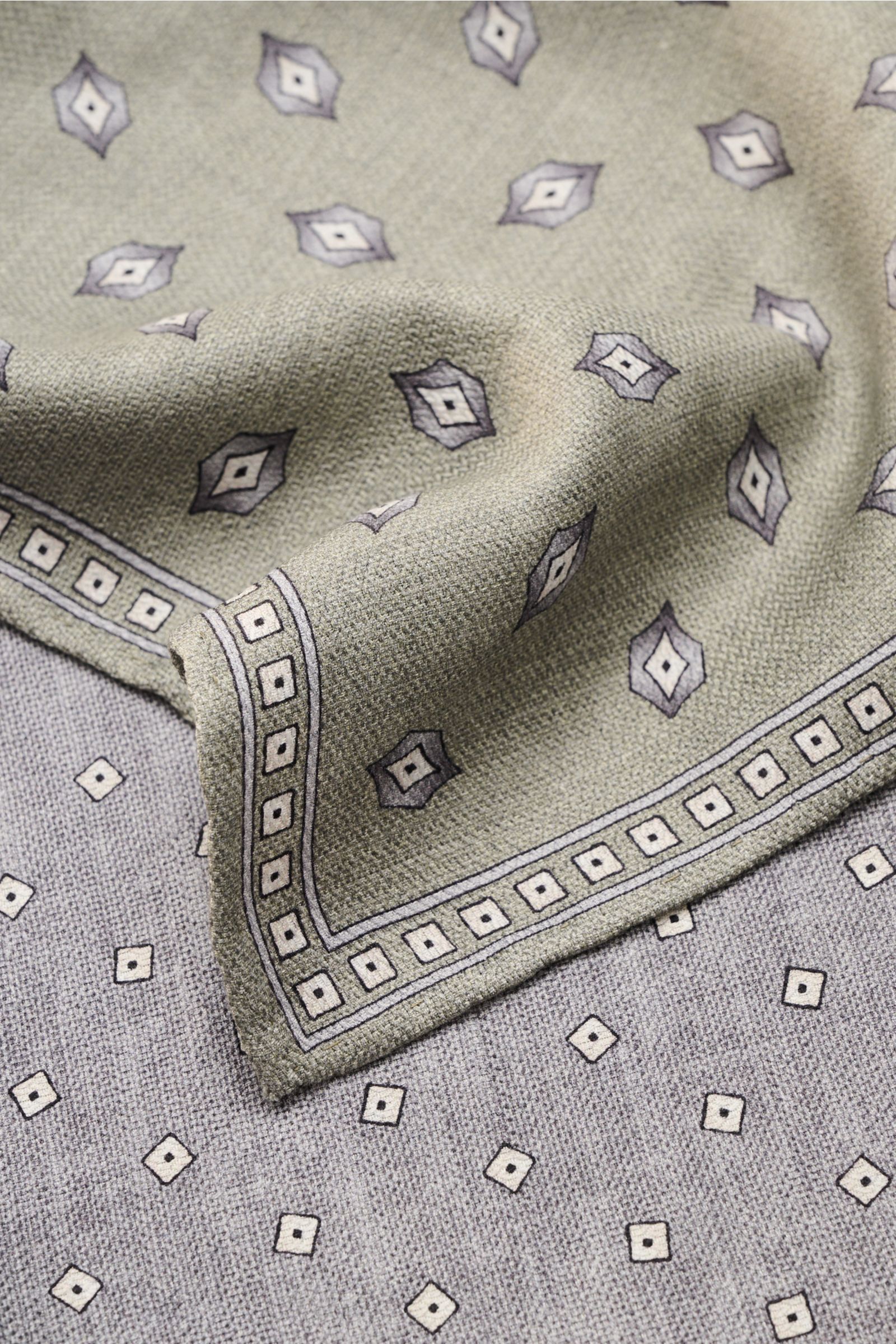 Close-up view of the Brunello Cucinelli Seiden-Einstecktuch dunkelrot/grau gepunktet, showing its dark red and gray dotted silk fabric with hand-rolled edges. Features: 

reine Seide
geschmeidiger Griff
Punktemuster
hand