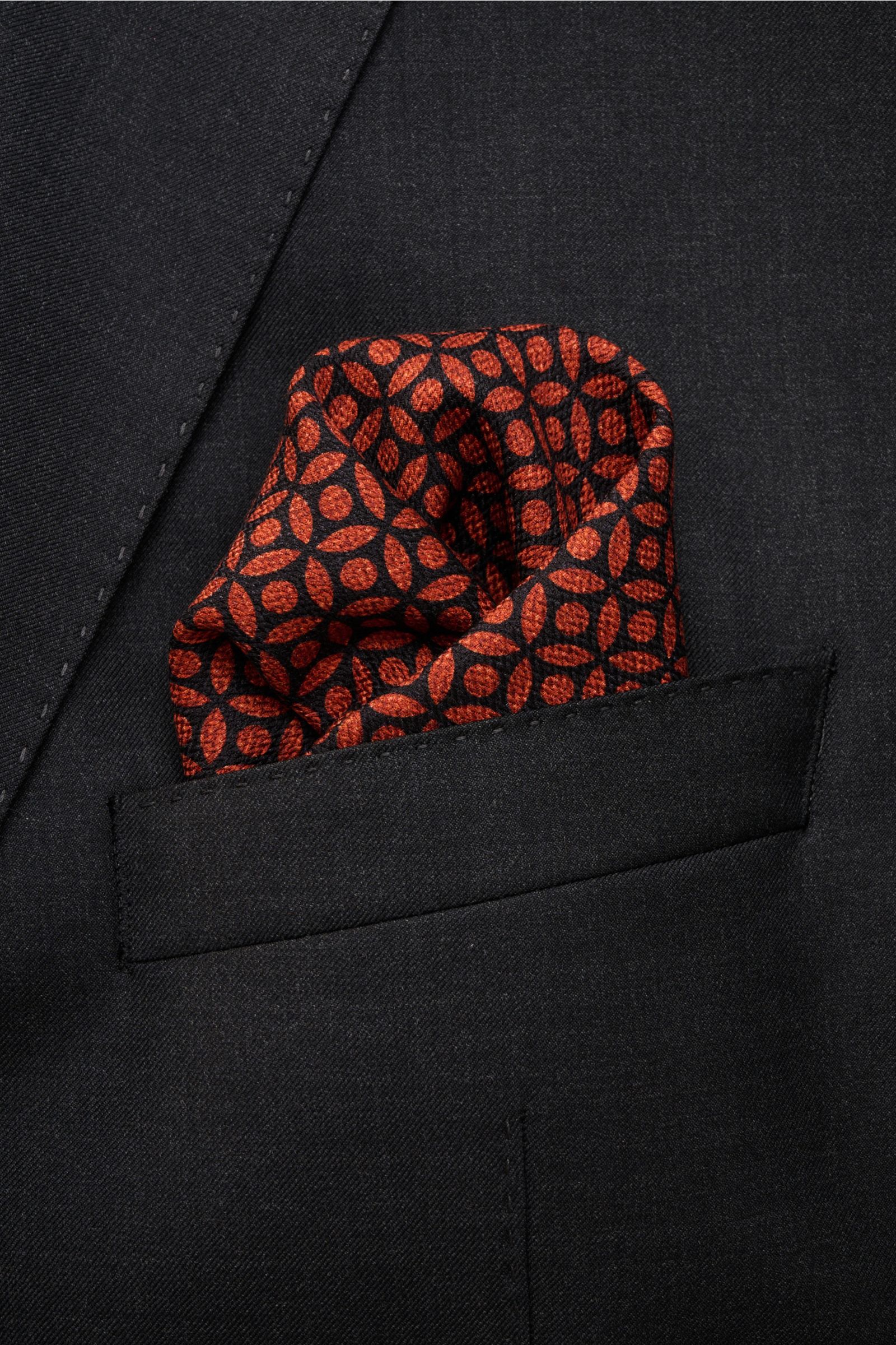 Brunello Cucinelli Silk pocket square red brown/dark navy patterned, floral pattern with hand-rolled edges, smooth touch, pure silk, approx. 35x35 cm, made in Italy, shown from a close-up front angle tucked in a black jacket pocket.