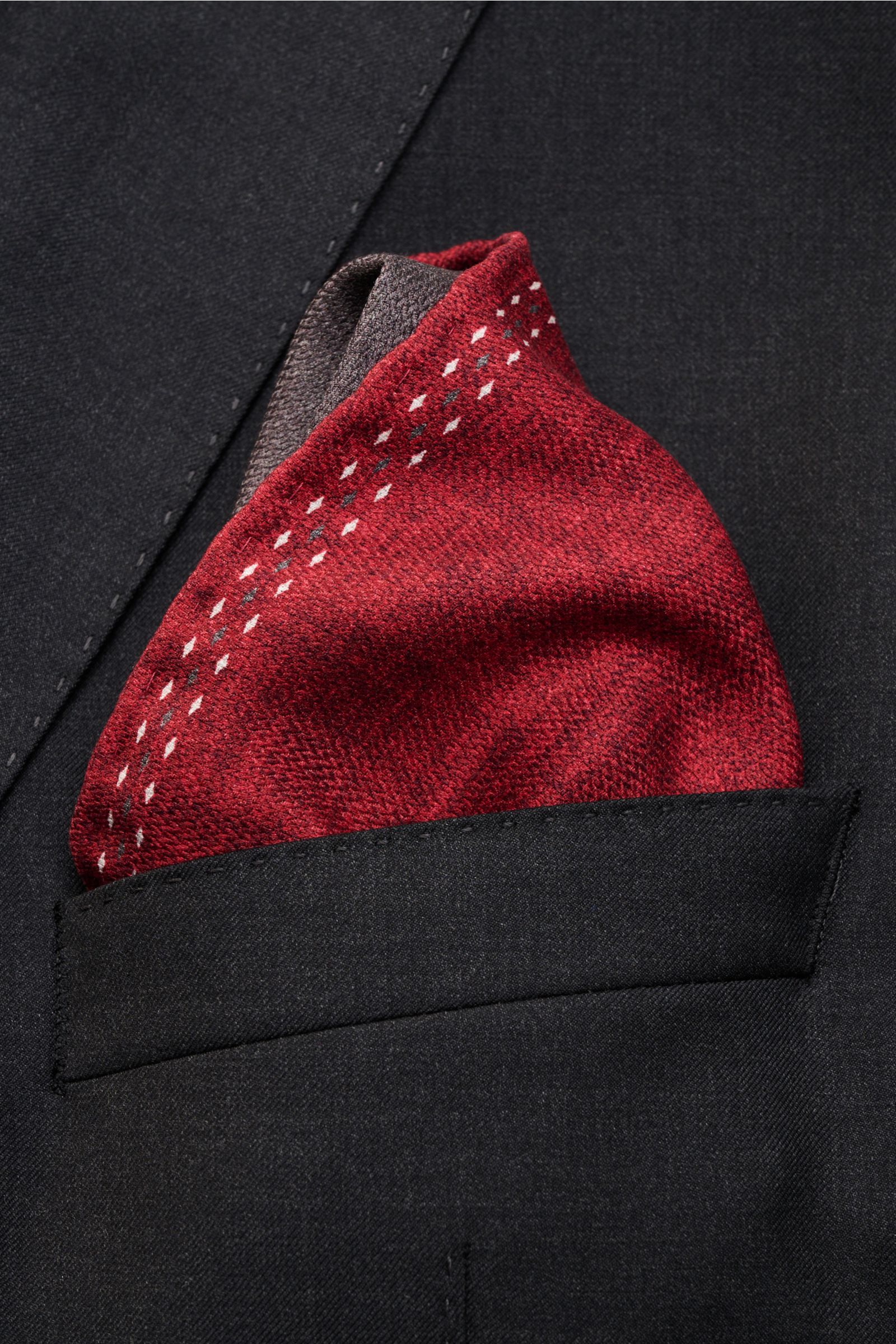 Close-up front view of Brunello Cucinelli Seiden-Einstecktuch dunkelrot/dunkelgrau in a black jacket pocket, made of reine Seide, geschmeidiger Griff, handrollierte Kanten, Made in Italy, Maße: ca. 35 cm x 35 cm.