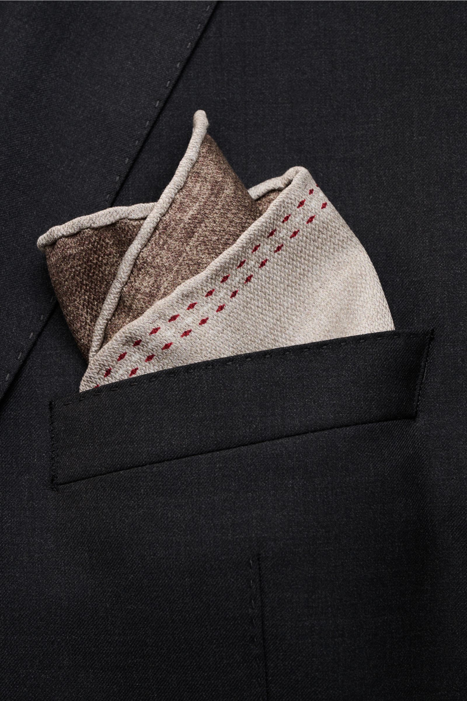 Close-up, slightly angled view of a Brunello Cucinelli Seiden-Einstecktuch grau/braun meliert folded in a black jacket pocket, featuring reine Seide, geschmeidiger Griff, handrollierte Kanten, Made in Italy, Maße: ca. 35 cm x 35 cm.