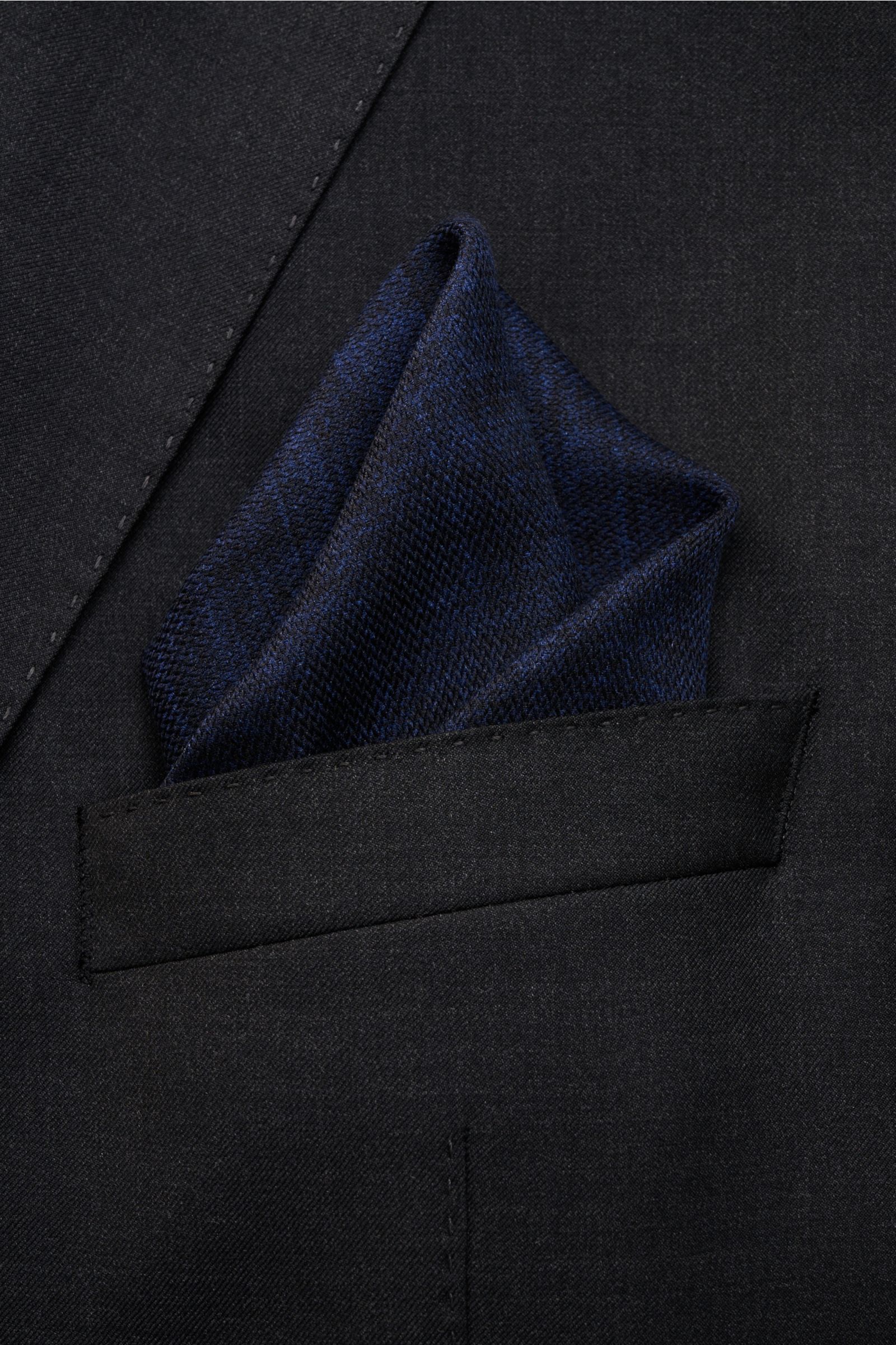 Brunello Cucinelli Seiden-Einstecktuch navy/blau meliert folded in a jacket pocket, photographed from above, reine Seide, geschmeidiger Griff, handrollierte Kanten, Made in Italy, Maße: ca. 35 cm x 35 cm