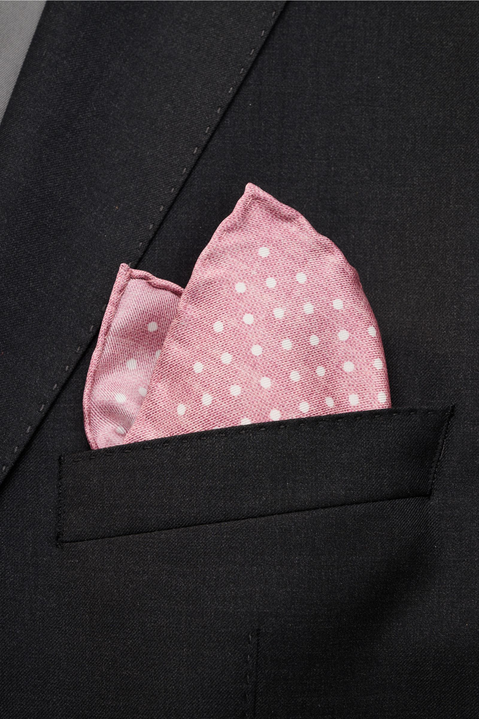 Rosi Collection Silk pocket square 'Silk' antique pink/white with polka dots, soft, smooth pure silk with rolled edges, made in Italy, approx. 31x31 cm, shown from close-up front angle tucked in black jacket pocket.