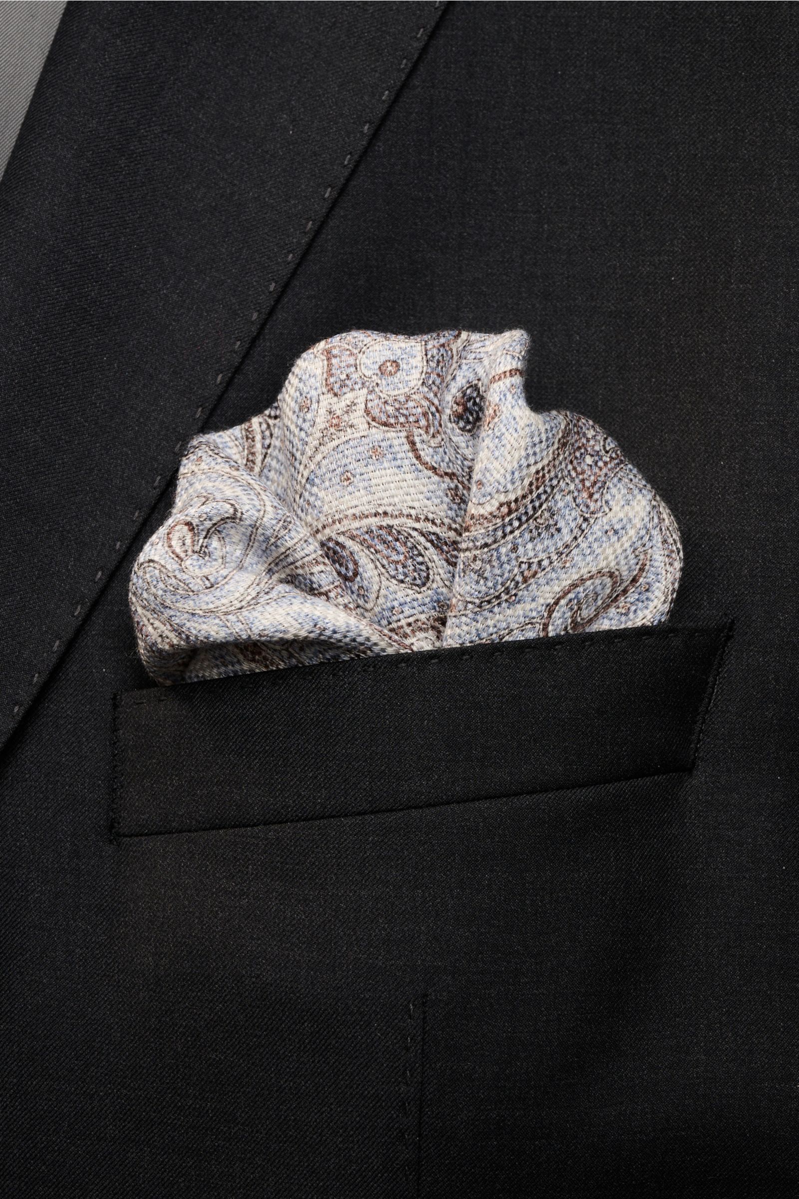 Alt tag (125 characters max): Front view of Rosi Collection Einstecktuch 'Joy' rauchblau/weiß/braun gemustert pocket square in black suit pocket.

Description: 
Eleganter Eyecatcher: Mit seinem modernen Paisley-Muster wird das Einstecktuch von ROSI COL