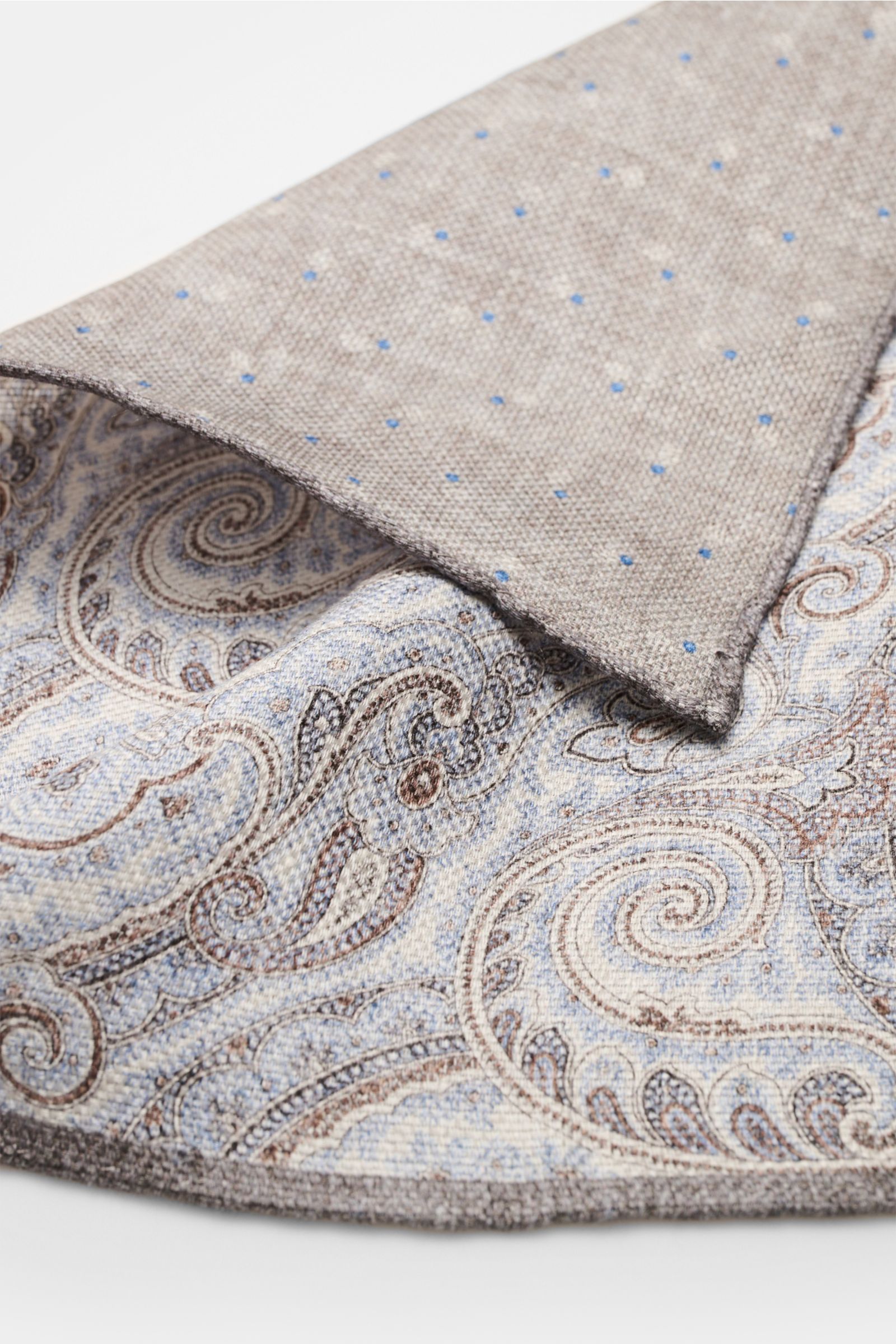 Close-up front angled view of the Rosi Collection Einstecktuch 'Joy' rauchblau/weiß/braun gemustert with paisley and dotted patterns.

Description: Eleganter Eyecatcher: Mit seinem modernen Paisley-Muster wird das Einstecktuch von ROSI COLLECTION zum h