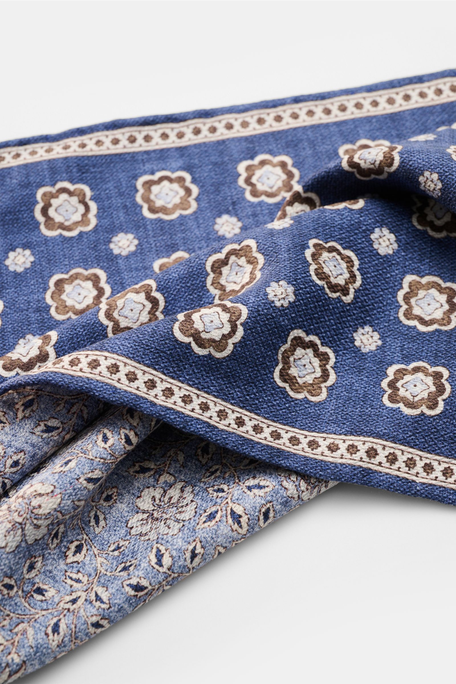 Rosi Collection Seiden-Einstecktuch 'Easy' dunkelblau/braun/hellblau gemustert, reine Seide, Medaillon-Print, florale Rückseite, rollierte Kanten, Made in Italy, ca. 31x31 cm, Detailaufnahme schräg von oben.