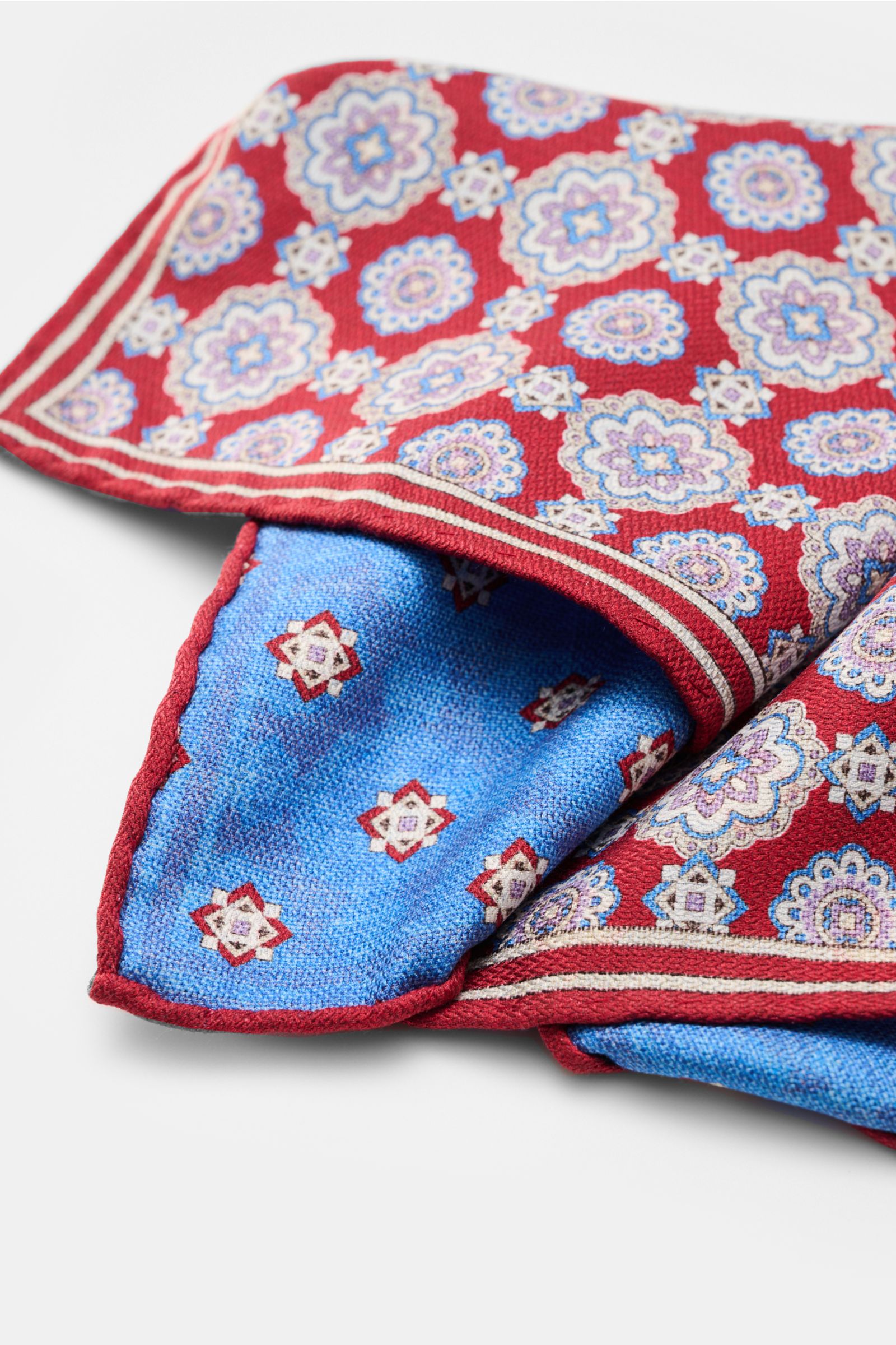 Rosi Collection Seiden-Einstecktuch 'Easy' rot/blau/flieder gemustert, reine Seide, Medaillon-Print, kontrastierende Rückseite, rollierte Kanten, ca. 31x31 cm, Made in Italy, Detailaufnahme von oben schräg.