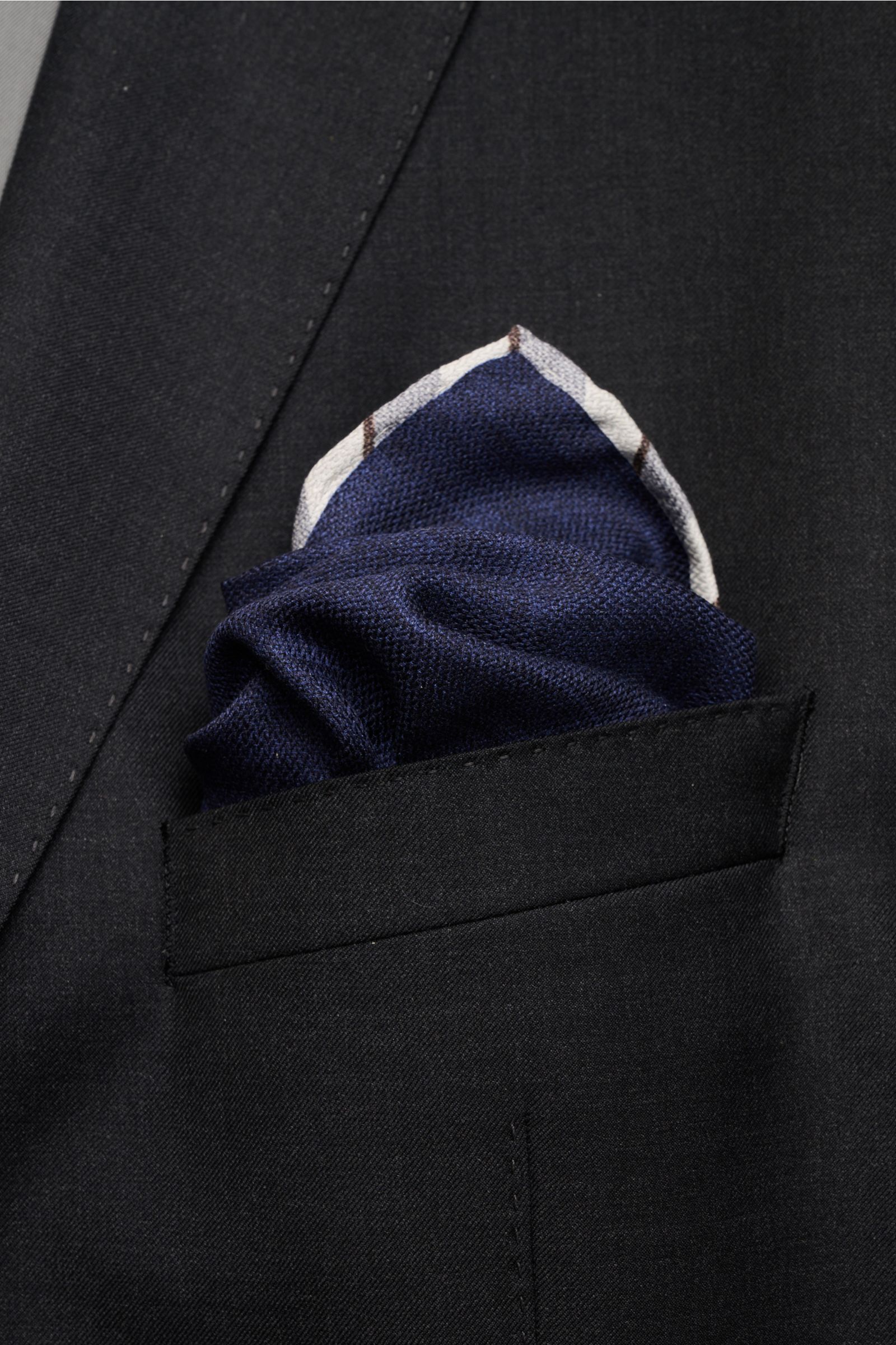 Close-up front view of a navy and smoke blue Brunello Cucinelli Seiden-Einstecktuch pocket square in a black blazer pocket, showcasing its silk texture.

Quiet Luxury kann BRUNELLO CUCINELLI besonders gut und bringt auch in dieser Saison passende Einst