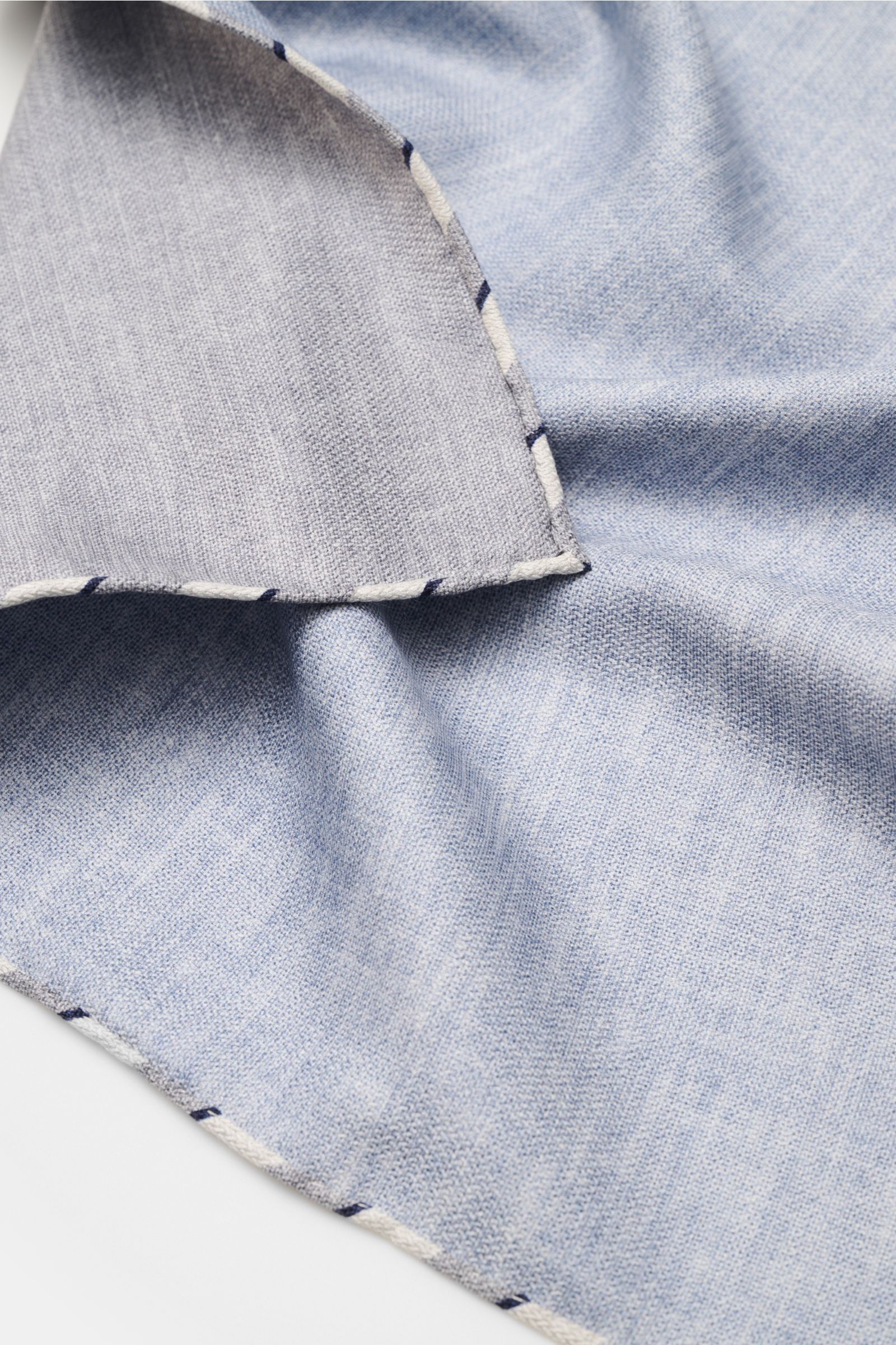 Close-up shot from above of the Brunello Cucinelli Seiden-Einstecktuch rauchblau meliert, a soft light blue silk pocket square with hand-rolled edges and a subtle melange pattern.

Quiet Luxury kann BRUNELLO CUCINELLI besonders gut und bringt auch in d