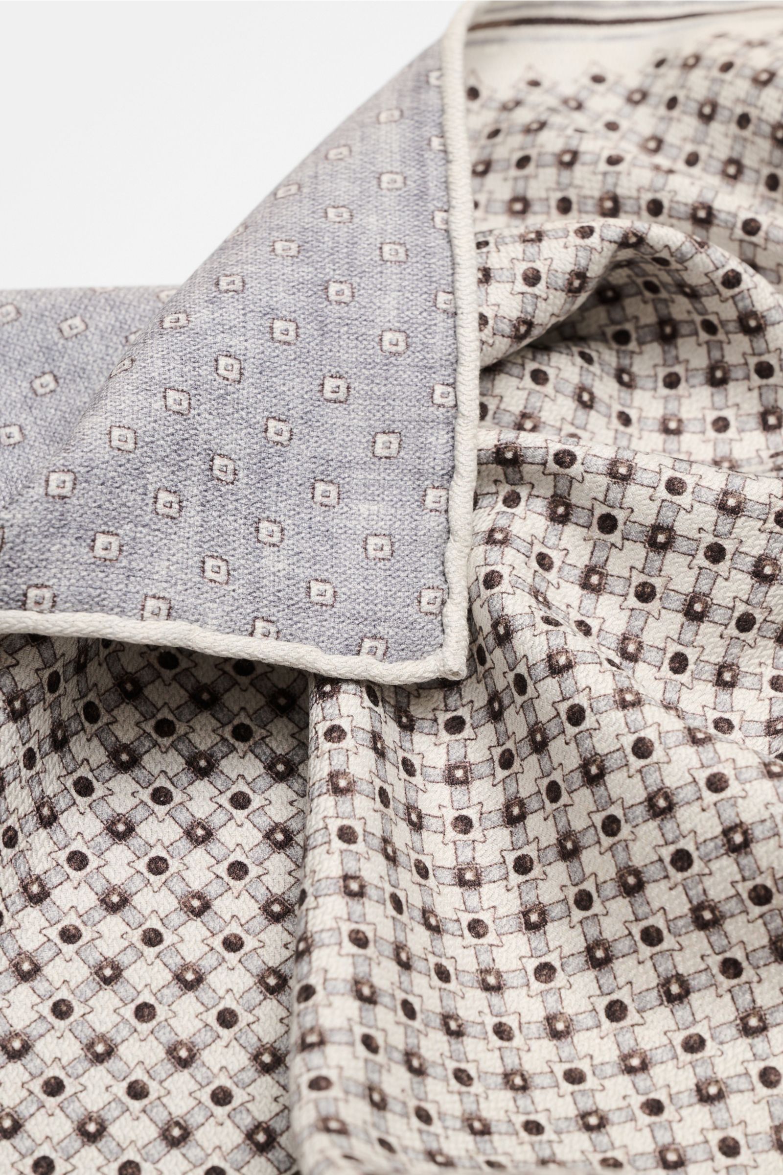 Nahaufnahme des Brunello Cucinelli Seiden-Einstecktuchs sand/dunkelbraun/grau gemustert mit grafischem Print, rollierten Kanten und unterschiedlicher Vorder- und Rückseite aus reiner Seide.