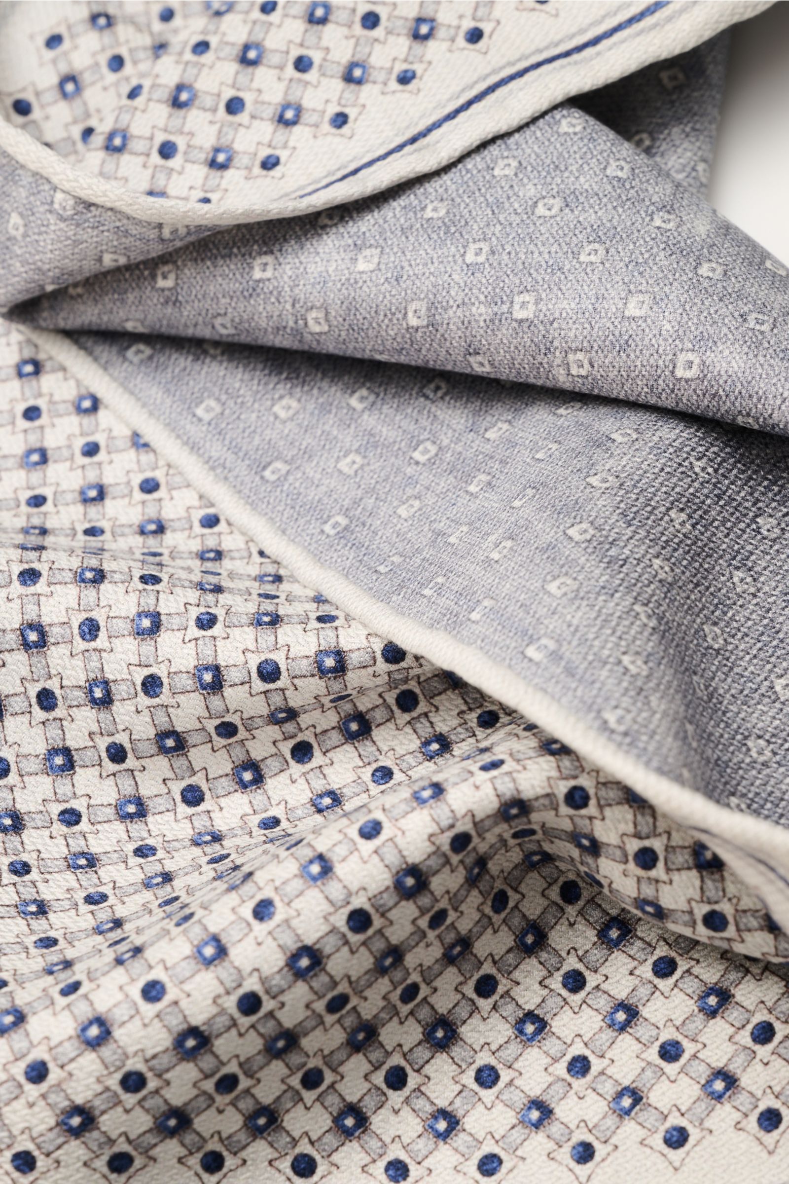 Brunello Cucinelli Seiden-Einstecktuch sand/navy/grau gemustert, weich fallend, doppelseitig mit grafischem Print und rollierten Kanten, Nahaufnahme.