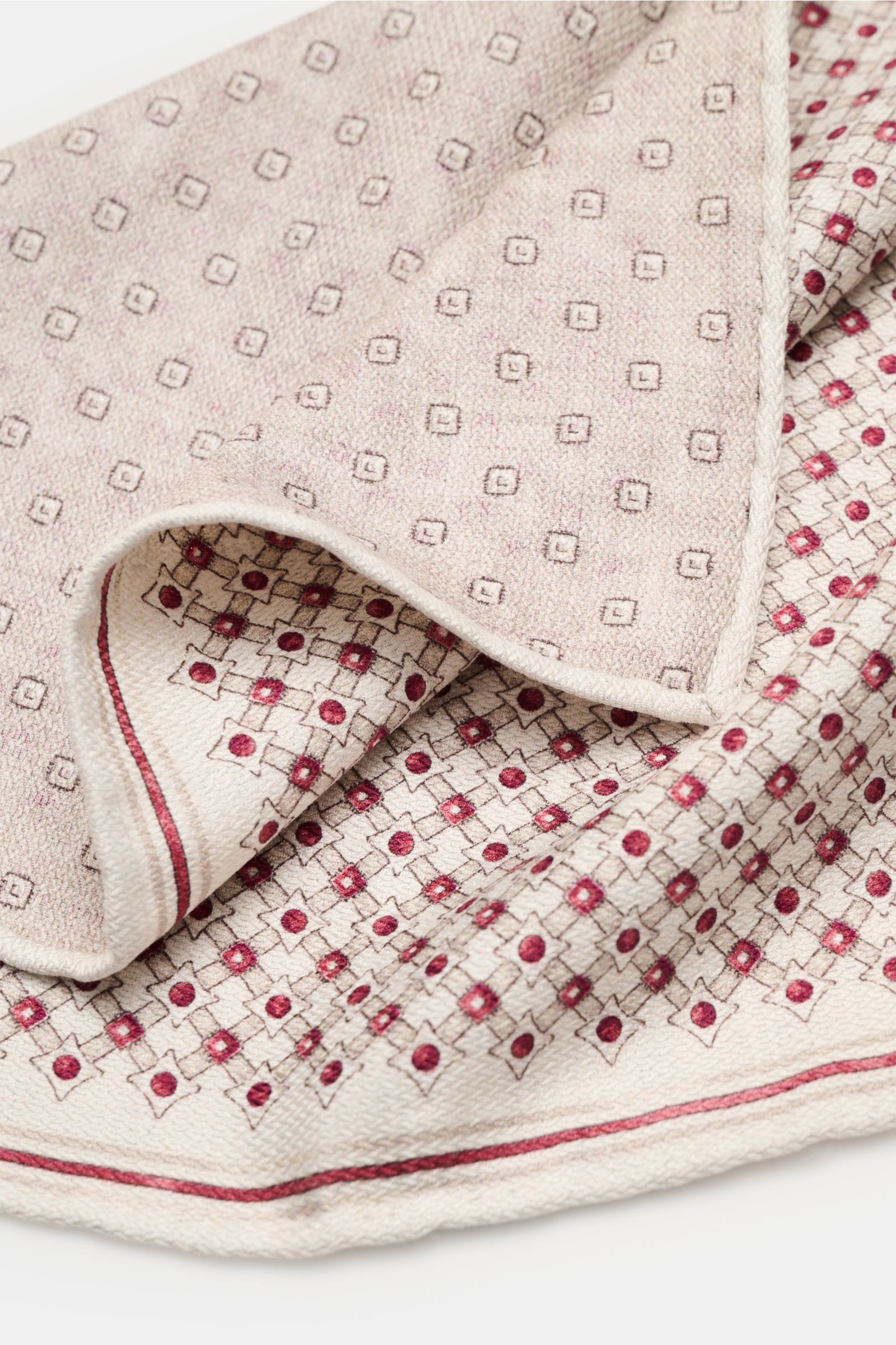 Close-up top-down view of the Brunello Cucinelli Silk pocket square sand/dark red/beige patterned, showing its graphic print with rolled edges and different front and back patterns.

Elegant and eye-catching: This pocket square in pure silk by BRUNELLO