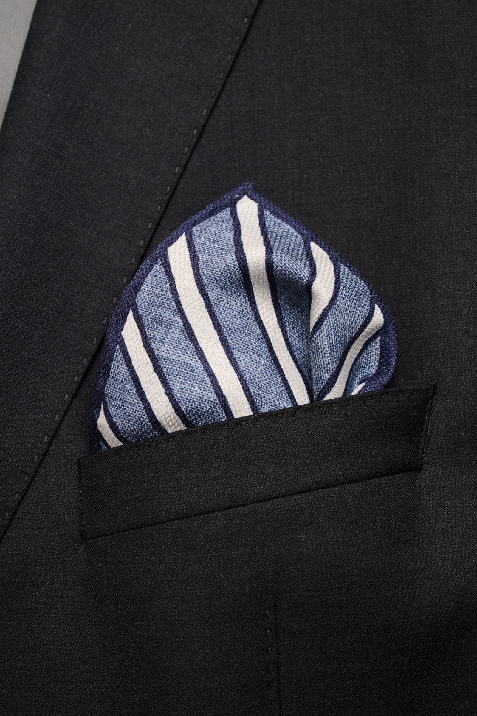 Brustnah fotografiertes, gestreiftes Brunello Cucinelli Seiden-Einstecktuch graublau/hellgrau/navy mit handrollierten Kanten.