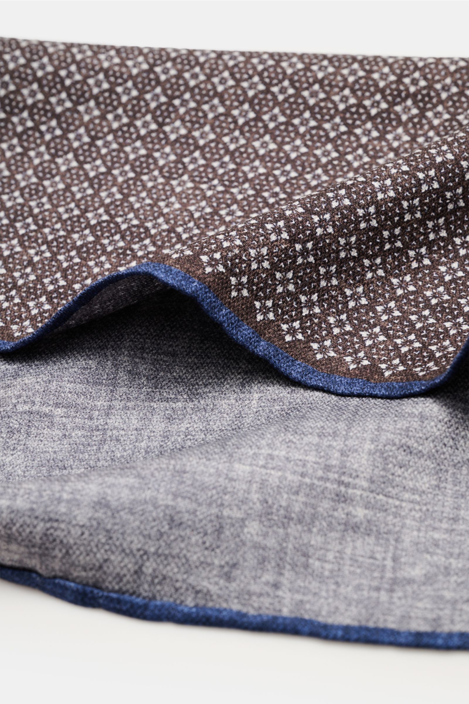 Close-up side view of Brunello Cucinelli Seiden-Einstecktuch dunkelbraun/navy/sand gemustert with floral pattern, navy hand-rolled edges, showing both front and back.

Quiet Luxury heißt der große Trend: Das kann BRUNELLO CUCINELLI besonders gut und br