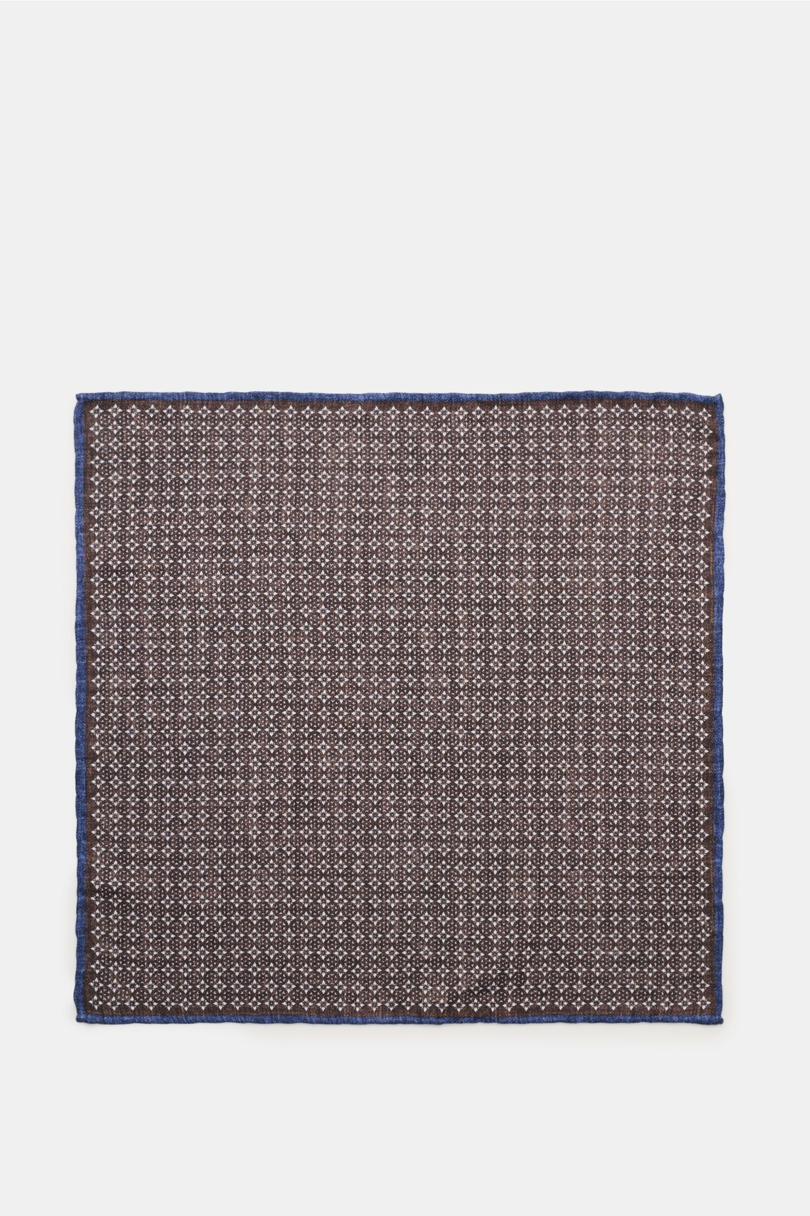 Top-down view of a Brunello Cucinelli Seiden-Einstecktuch dunkelbraun/navy/sand gemustert pocket square with a subtle floral pattern, navy border, and handrolled edges. Quiet Luxury heißt der große Trend: Das kann BRUNELLO CUCINELLI besonders gut und b