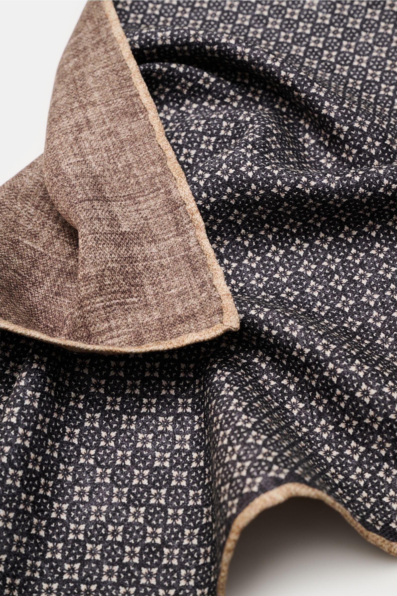 Brunello Cucinelli Seiden-Einstecktuch anthrazit/graubraun/sand gemustert shown from an angled close-up, highlighting floral patterns and hand-rolled edges. 

Quiet Luxury heißt der große Trend: Das kann BRUNELLO CUCINELLI besonders gut und bringt auch