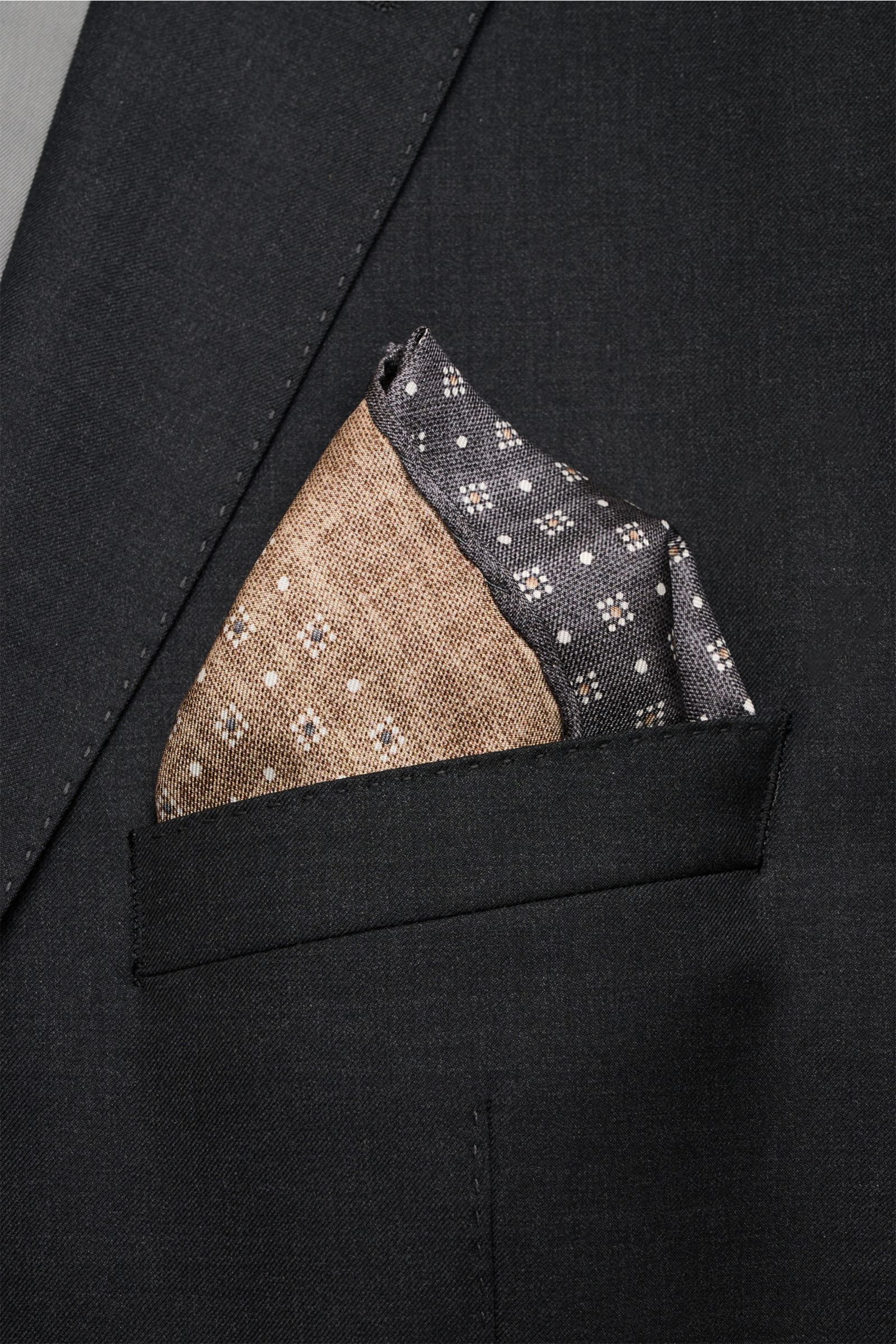 Alt tag (max 125 characters): Close-up front view of Brunello Cucinelli Seiden-Einstecktuch dunkelgrau/graubraun/weiß gemustert in a suit pocket.

Quiet Luxury kann BRUNELLO CUCINELLI besonders gut und bringt auch in dieser Saison passende Einstecktüch