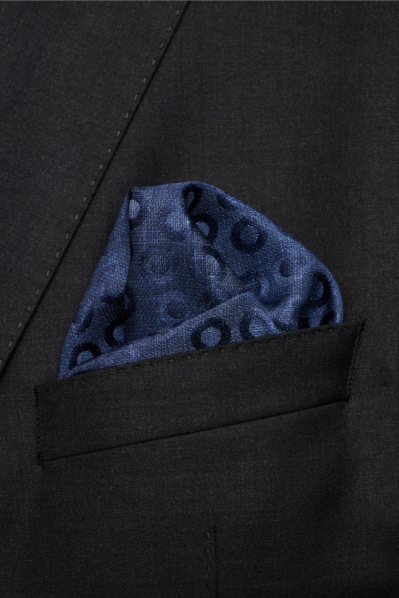 Close-up front view of Brunello Cucinelli Seiden-Einstecktuch navy/graublau gepunktet silk pocket square with a subtle polka dot pattern tucked into a black suit jacket pocket.

Quiet Luxury heißt der große Trend: Das kann BRUNELLO CUCINELLI besonders 