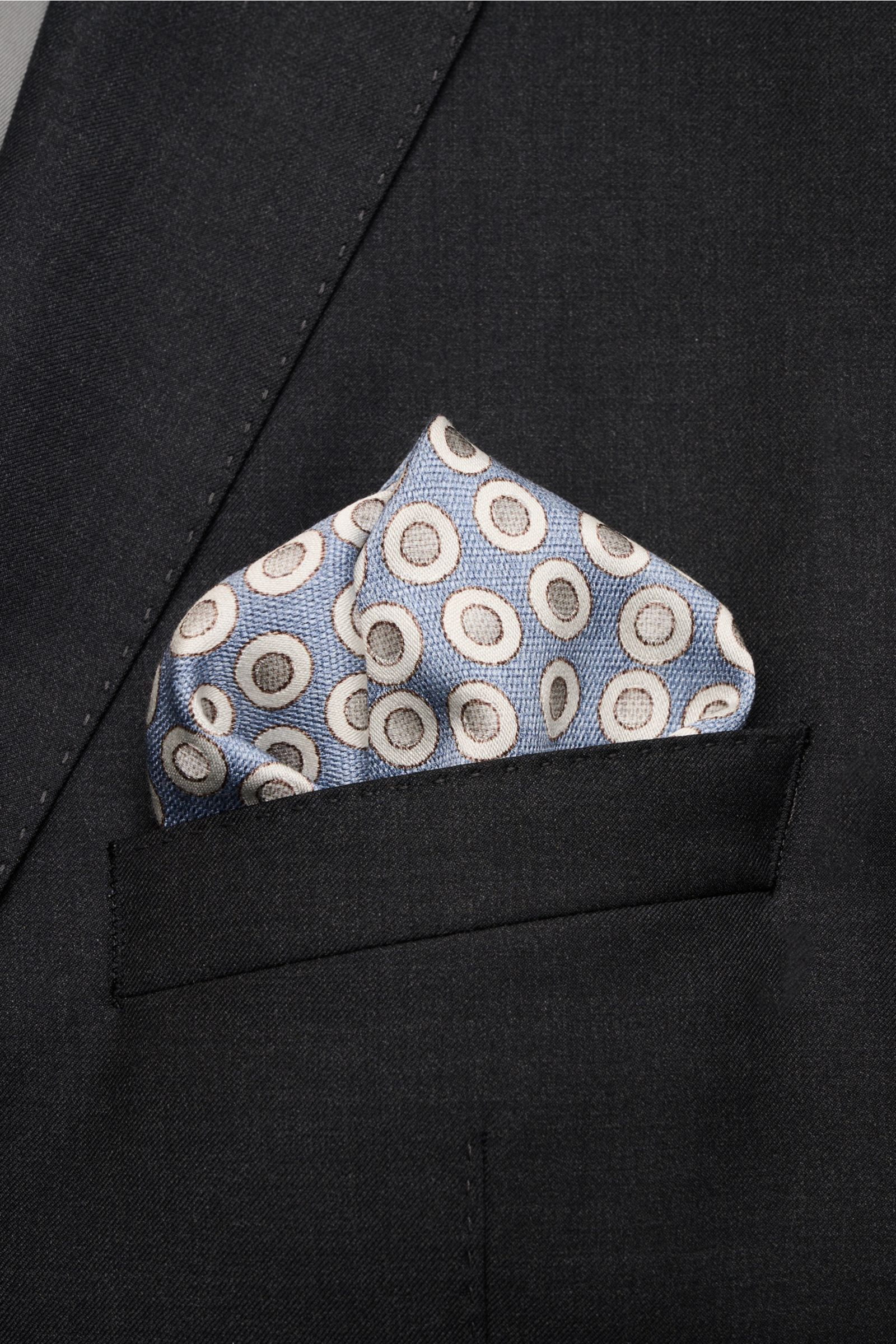 Close-up front view of Brunello Cucinelli Seiden-Einstecktuch rauchblau/silbergrau gepunktet pocket square in black suit pocket, pure silk, smooth feel, dotted pattern, hand-rolled edges, Made in Italy, approx. 35x35 cm. Quiet Luxury heißt der große Trend