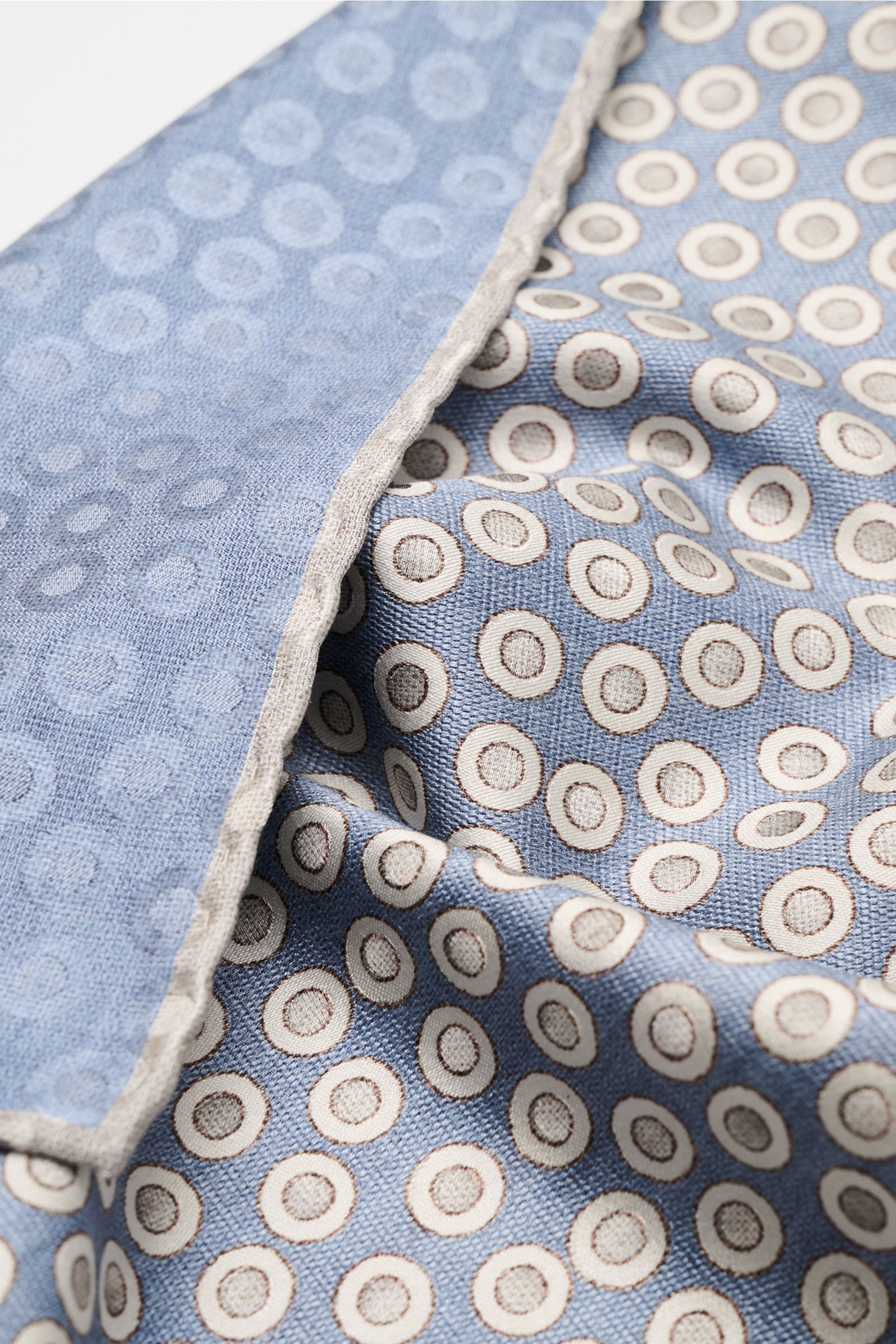Close-up angled view of the Brunello Cucinelli Seiden-Einstecktuch rauchblau/silbergrau gepunktet, a silk pocket square with smooth texture and subtle polka dot pattern, hand-rolled edges, made in Italy, approx. 35 cm x 35 cm. Quiet Luxury heißt der große