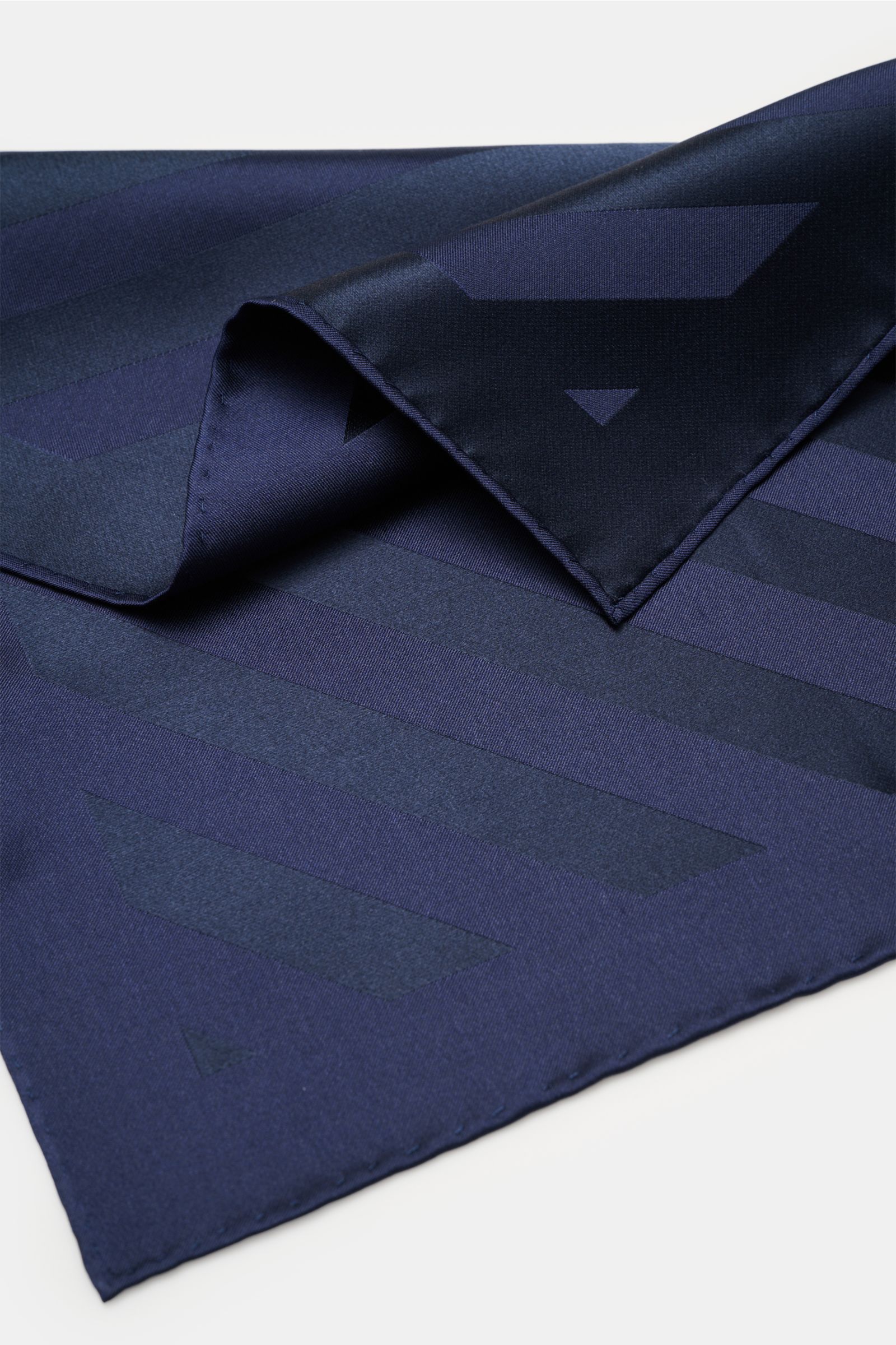 Brunello Cucinelli Seiden-Einstecktuch dunkelblau/dark navy gestreift, reine Seide, edles Streifenmuster, rollierte Kanten, glatter Griff, liegend aus schräger Perspektive.