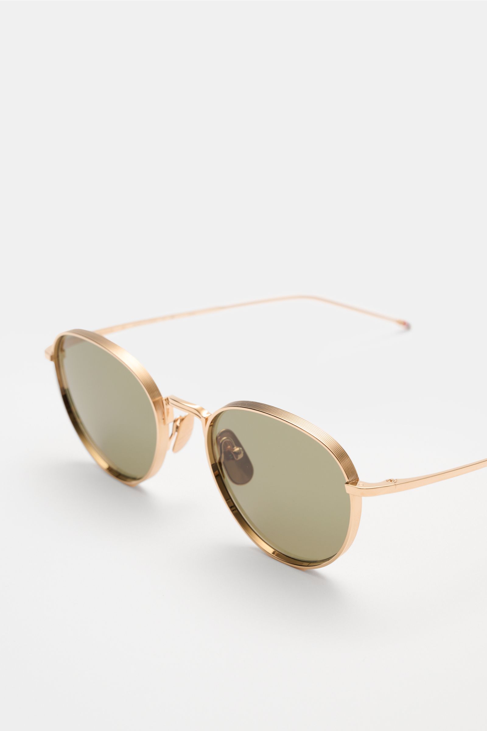 Thom Browne Sonnenbrille gold, runde abgerundete Form, tiefer Metallrahmen, getönte Gläser mit 100% UV-Schutz, Tricolore-Detail am Bügel, seitliche Perspektive.