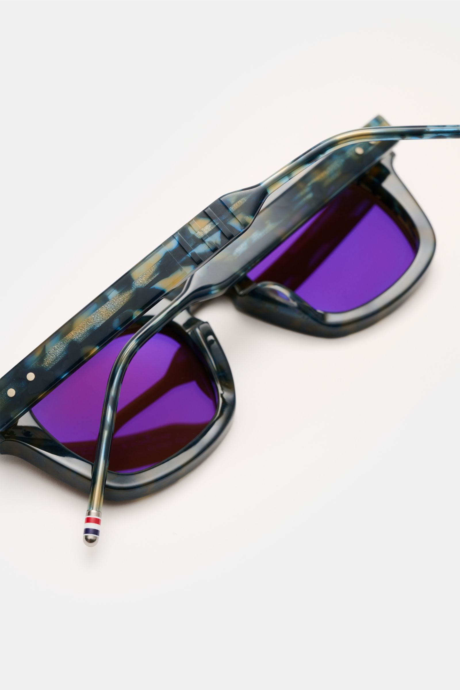 Thom Browne Sonnenbrille dunkelblau gemustert, eckige Notched-Bridge-Form, Acetat-Rahmen, violette Gläser, Detail am Bügel, Seitenansicht.