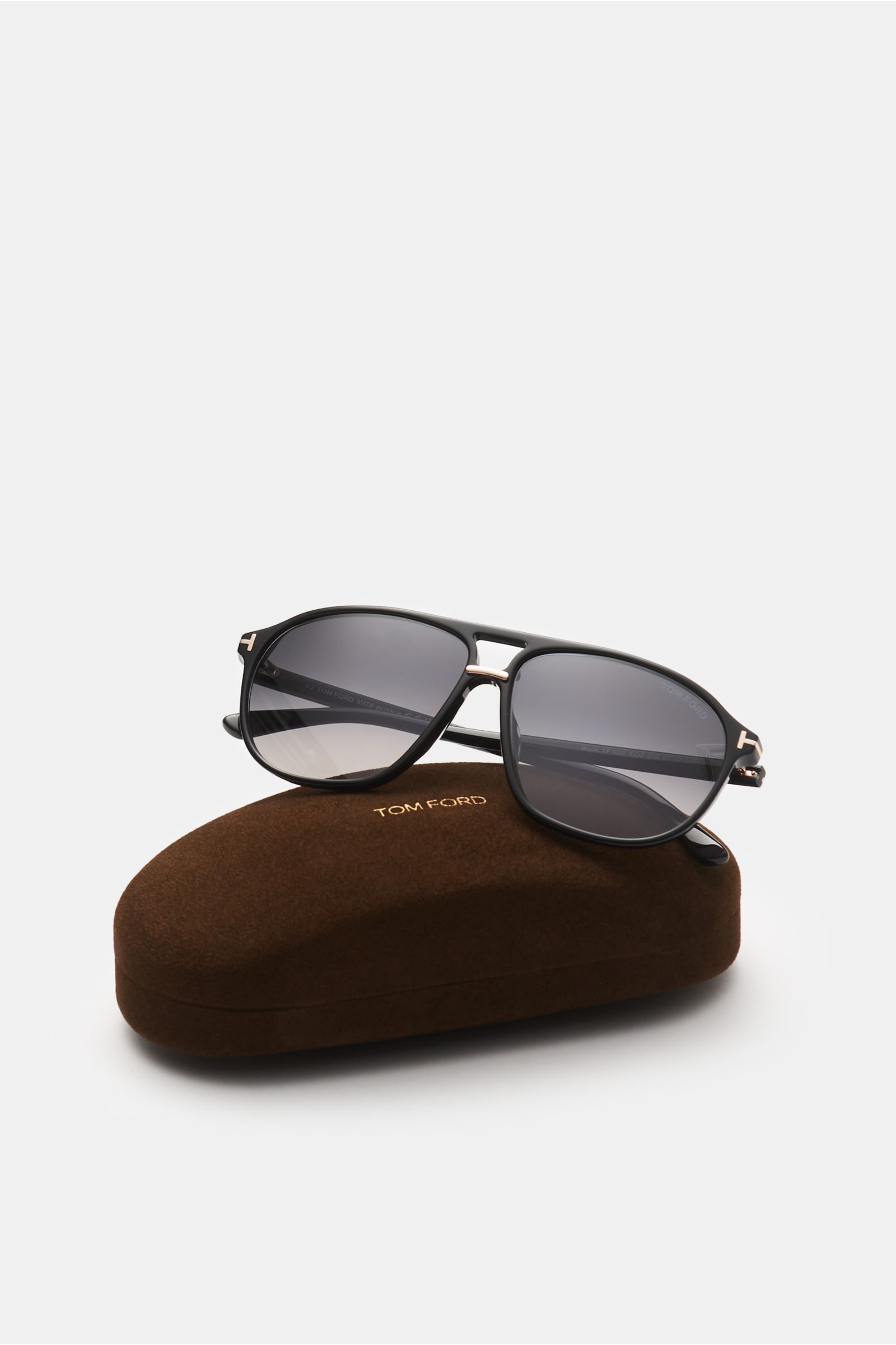 Tom Ford Sonnenbrille 'Bruce' schwarz im Navigator-Stil mit polarisierten, UV-geschützten Gläsern auf braunem Samt-Etui, frontale Perspektive.