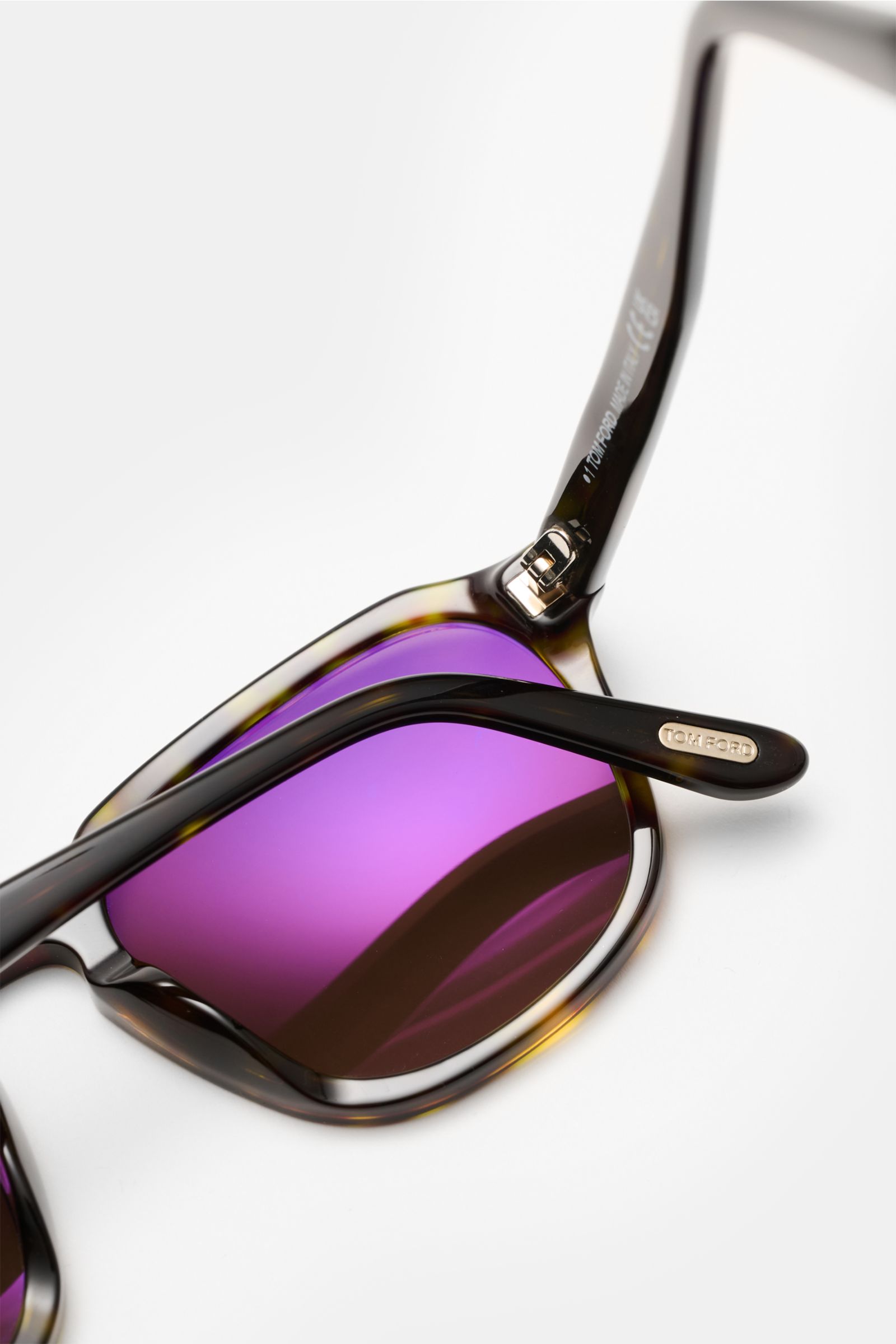 Close-up top view of Tom Ford Sunglasses 'Avery' green/dark brown patterned, square acetate frame, purple polarized lenses, with Tom Ford logo on temple tip.