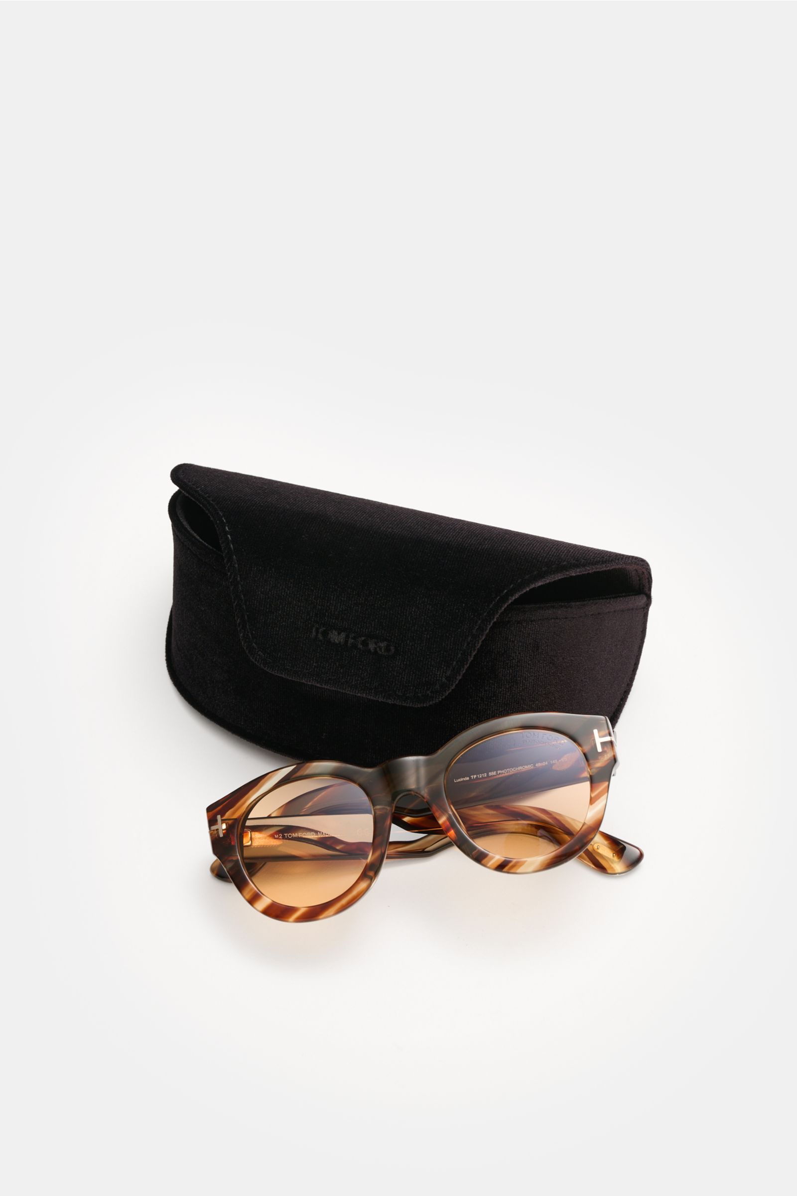Front perspective of Tom Ford Sonnenbrille 'Lucinda' braun/hellbraun gemustert with rounded silhouette, photochrome lenses, acetate frame, 100% UV protection, filter category 3, and black velvet hard case.

Description:  
Stilvoller Allrounder: Die mod