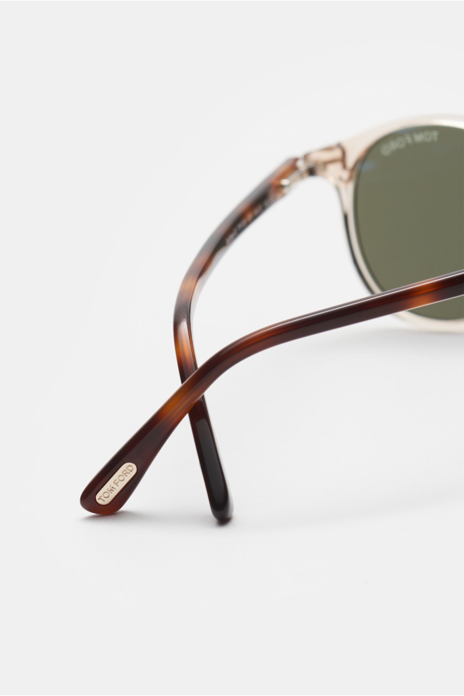 Close-up rear-side view of Tom Ford Sonnenbrille 'Andrea' beige/braun gemustert/grün with round silhouette, transparent acetate frame, tortoiseshell temples, and green plastic lenses.

Mit ihrer runden Form und alltagstauglichen Kunststoffgläsern ist d