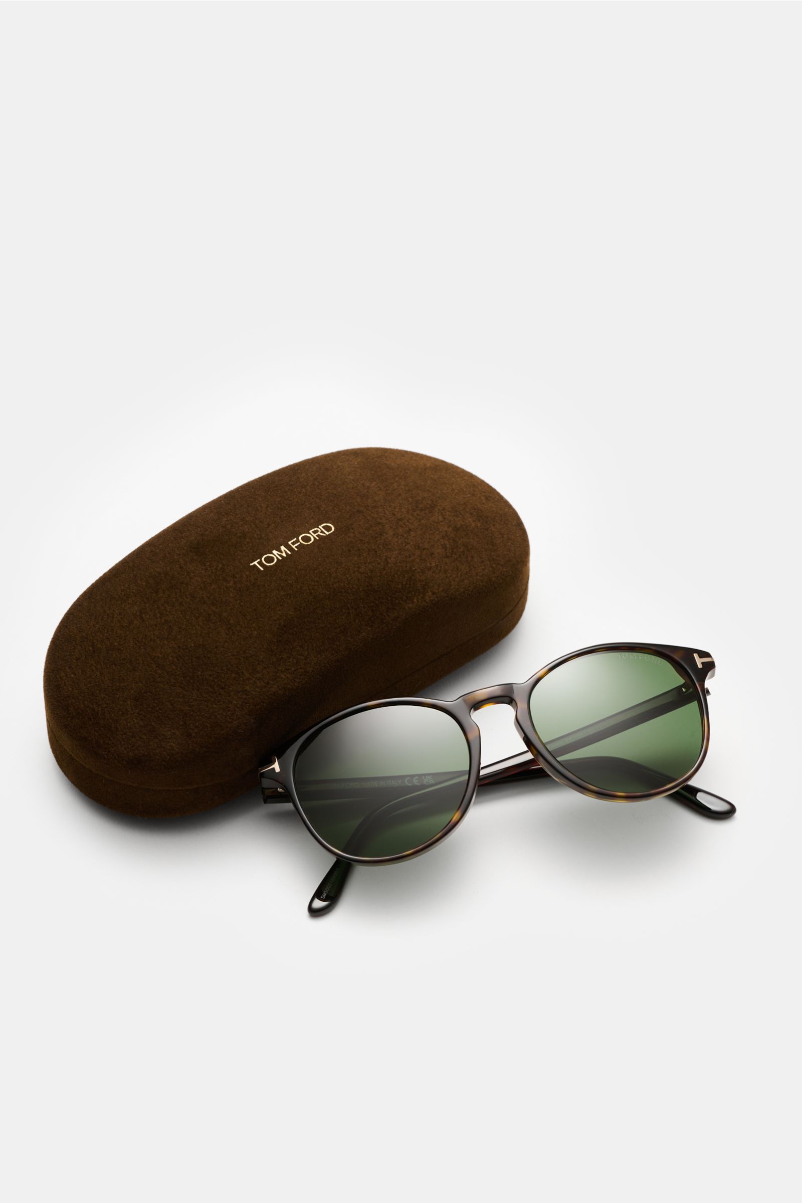 Tom Ford Sonnenbrille 'Lewis' dunkelbraun meliert mit leicht gerundeter Silhouette, melierter Optik, grün getönten Kunststoffgläsern, Acetat-Rahmen, 100% UV-Schutz, präsentiert neben braunem Samt-Hartschalenetui, seitliche Perspektive.