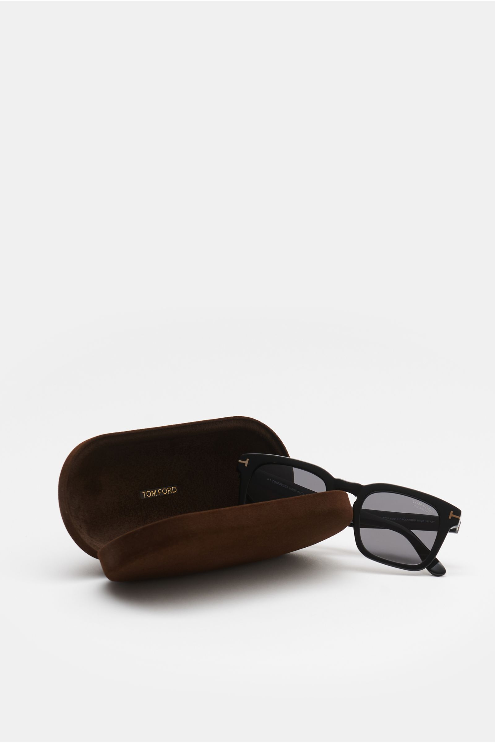 Tom Ford Sonnenbrille 'Dax' schwarz mit leicht eckiger Form, polarisierte Gläser, Acetat-Rahmen, 100% UV-Schutz, vor offenem Samt-Etui, seitliche Perspektive.