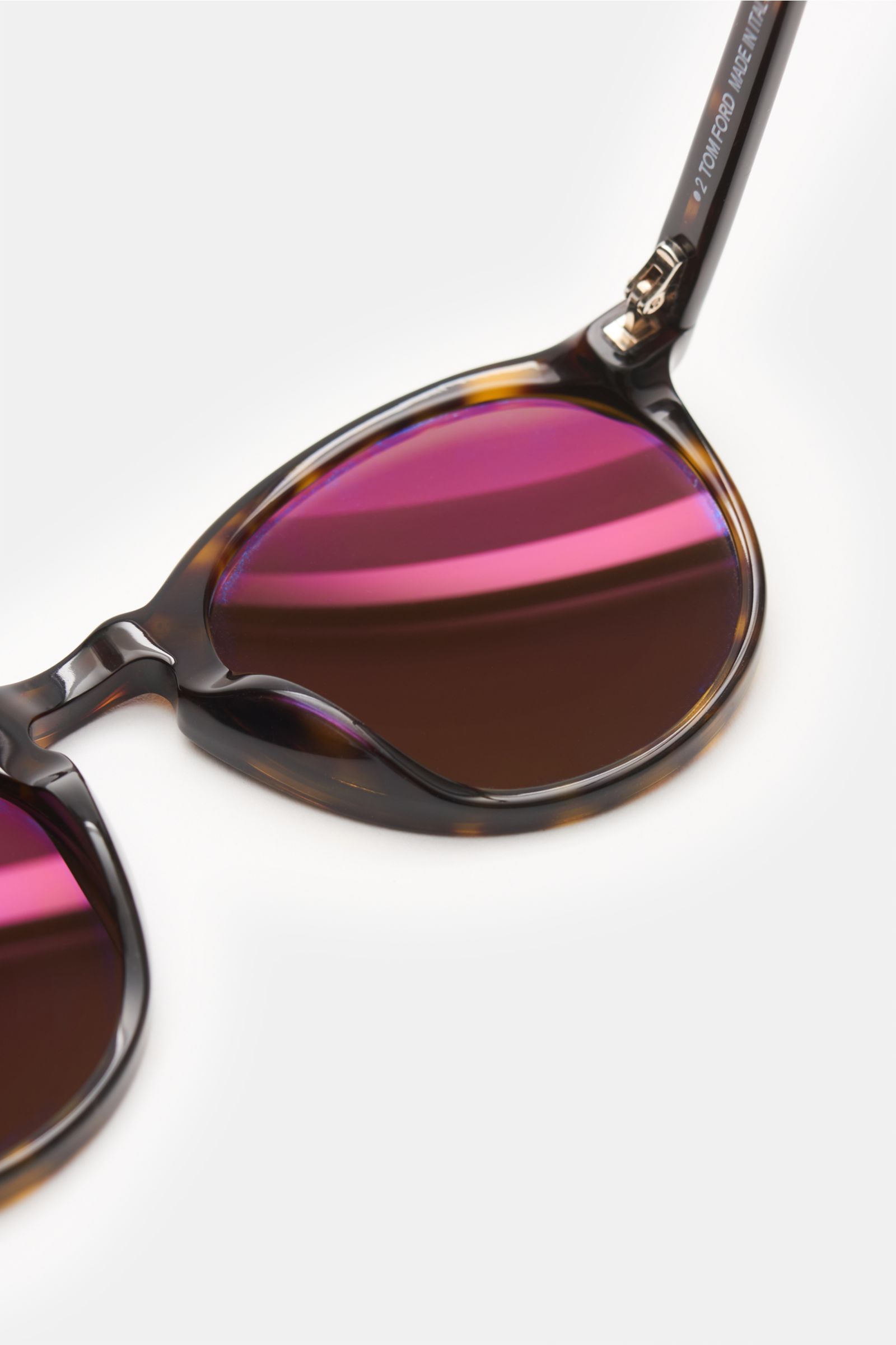 Close-up of the right lens and part of the frame of the Tom Ford Sonnenbrille 'Aurele' dunkelbraun gemustert/braun, photographed from a top-side angle. Nicht nur in Künstlerkreisen äußerst beliebt ist die Panto-Form, die TOM FORD für seine Sonnenbrille 'A