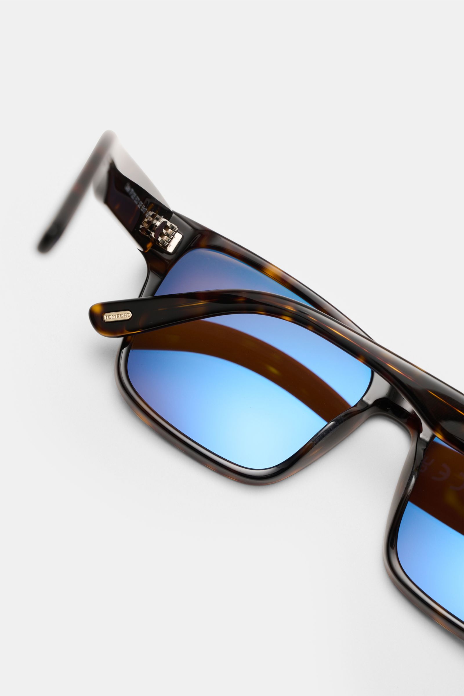 Close-up image of Tom Ford Sonnenbrille 'Calder' dunkelbraun/braun gemustert sunglasses from an angled side perspective, showcasing the Tortoise acetate frame with polarized blue lenses. Stilvoller Allrounder: Mit ihrem zeitlosen Tortoise-Design wird die 
