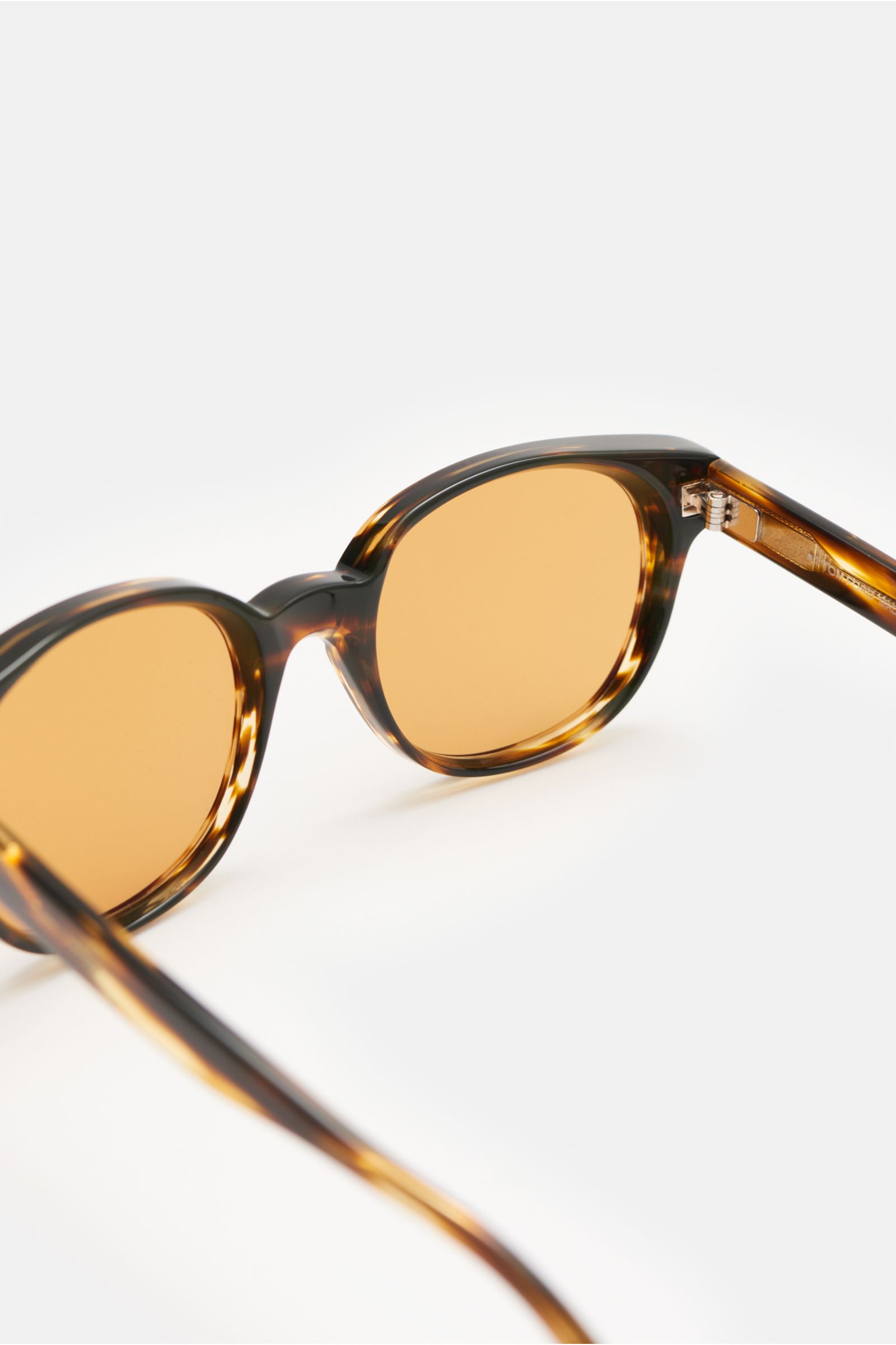 Tom Ford Sunglasses 'Mert' dark brown melange shown from a close-up rear angle, featuring a slightly rounded silhouette, mottled acetate frame, evenly tinted plastic lenses, 100% UV protection (filter category 3), and a velvet hard case included.