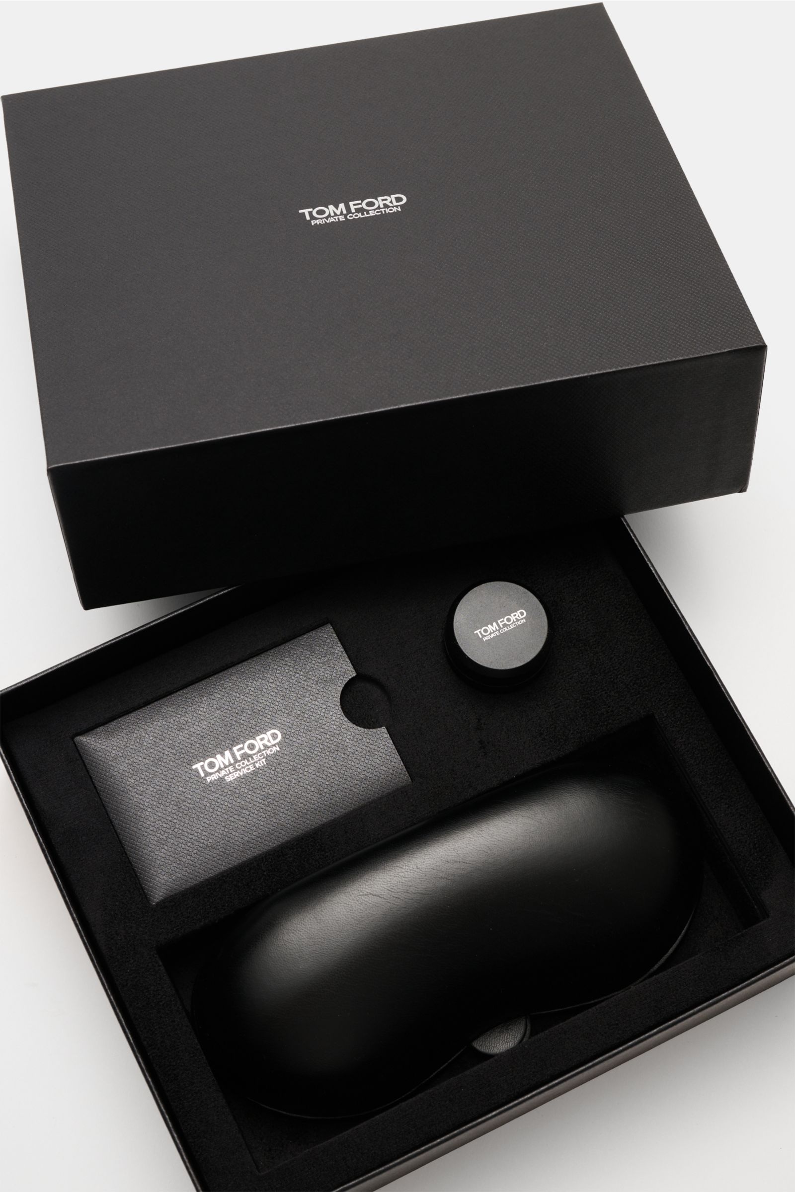 Tom Ford Horn-Sonnenbrille 'Private Collection' schwarz/grau/weiß gemustert mit Büffelhornrahmen, Lederetui und Politurset, Draufsicht in edler Verpackung.