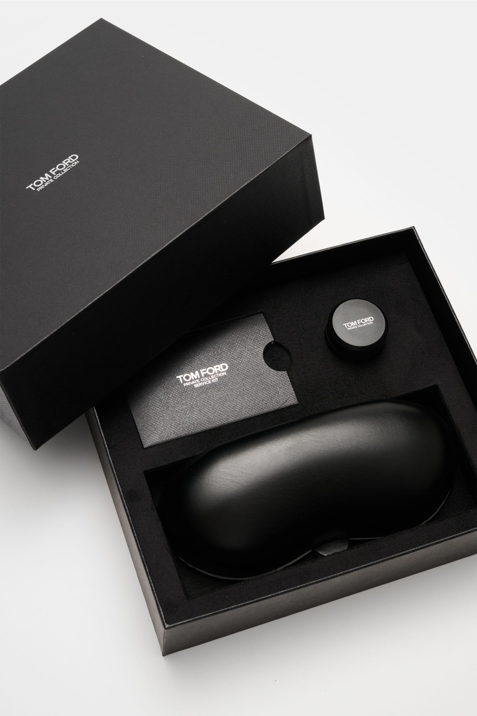 Geöffnete schwarze Tom Ford Horn-Sonnenbrille 'Private Collection' Verpackung von oben mit Leder-Hartschalenetui, Horn-Politurset und Service-Karte.