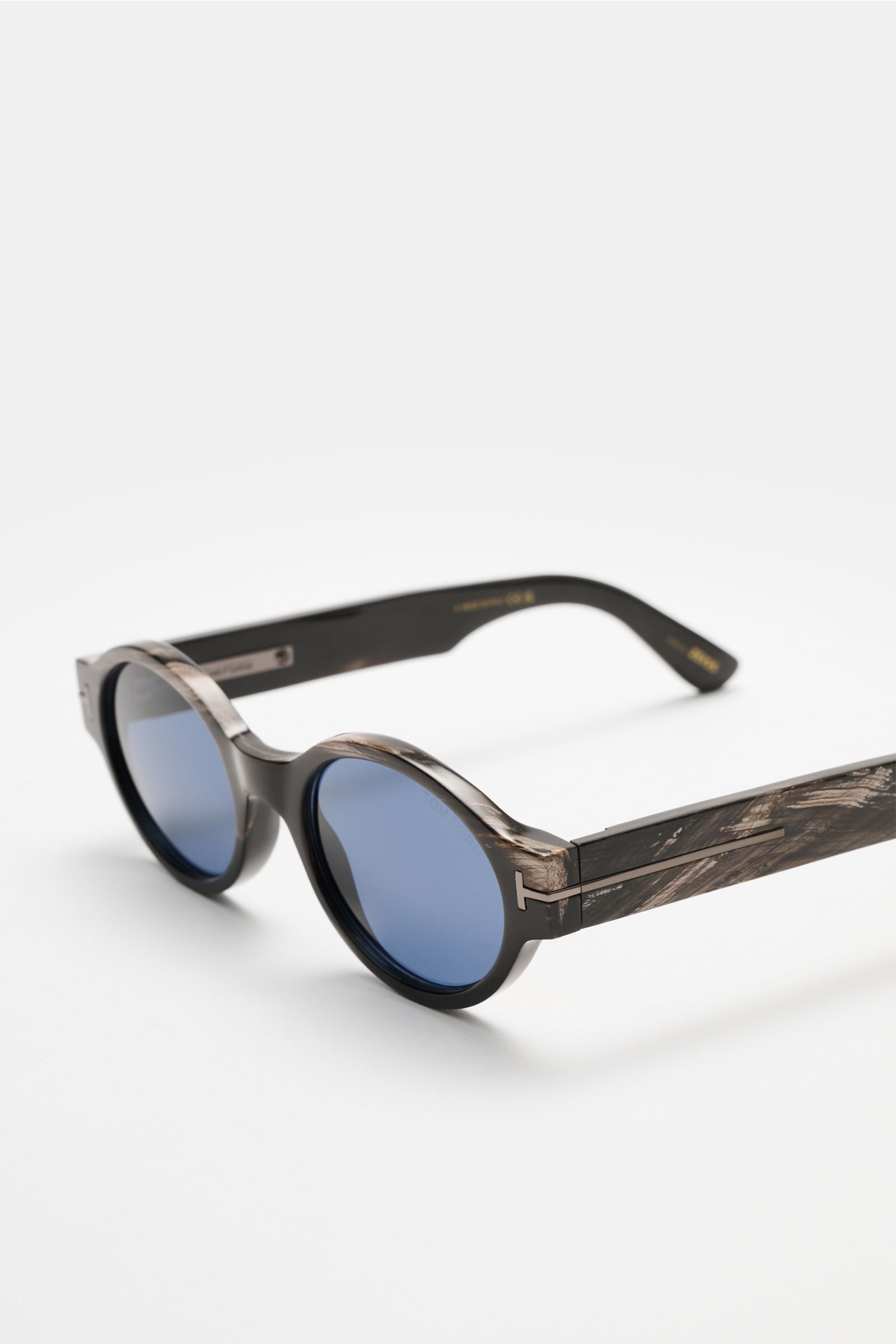Front-side angled view of Tom Ford Horn sunglasses 'Private Collection' black/grey/white patterned with round blue lenses and signature ‘T’ detail.

Description: The luxurious 'Private Collection' by TOM FORD only features exclusive designs worn by the